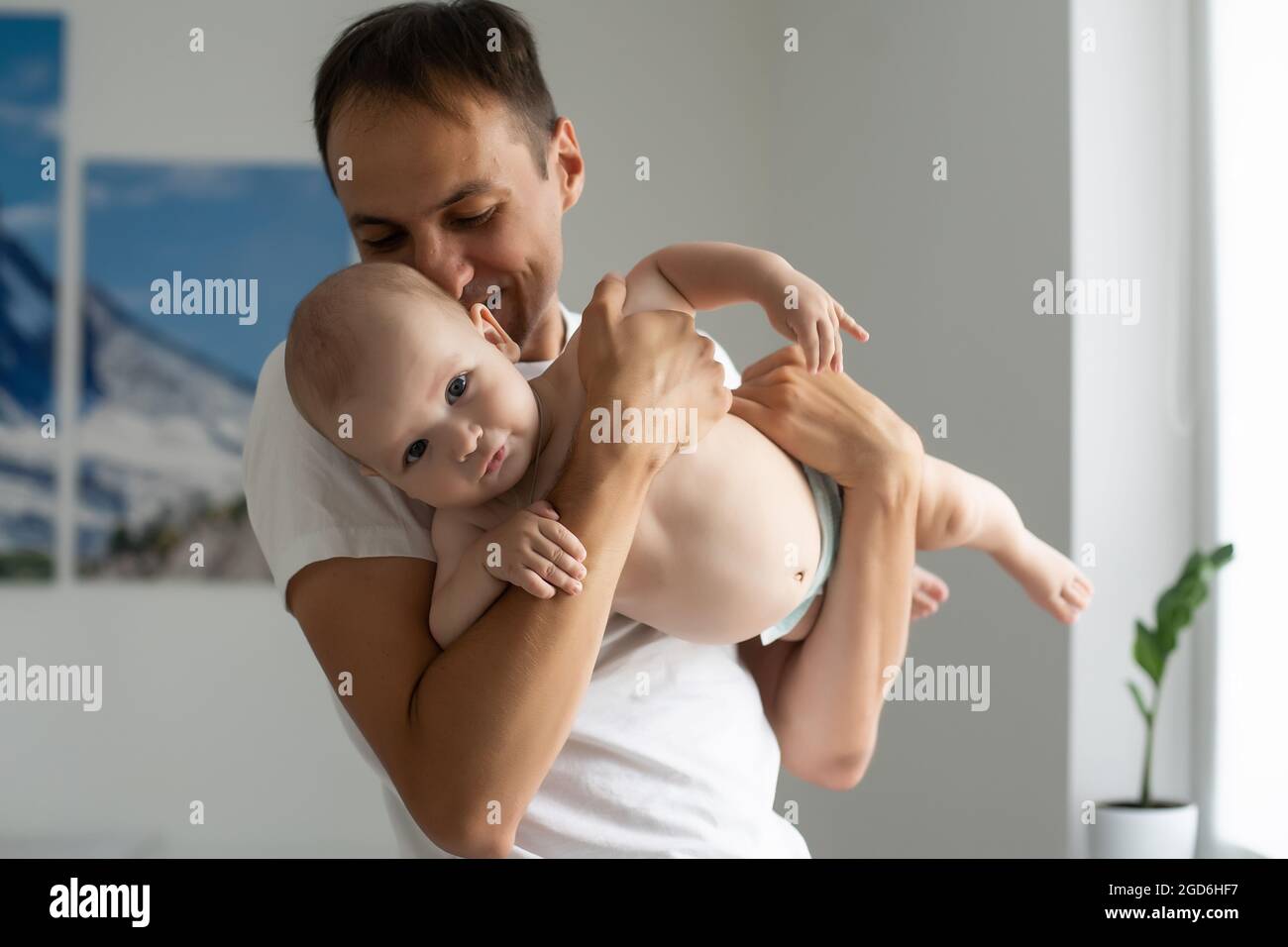 Father Hugging Newborn Baby in white bedroom. Stock Photo