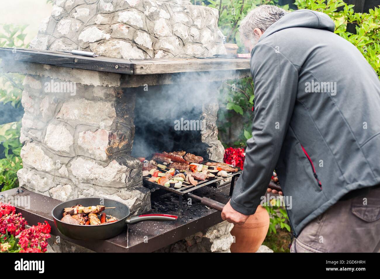 Man cooking meat on barbecue grill at bbq party in summer garden. Food ...