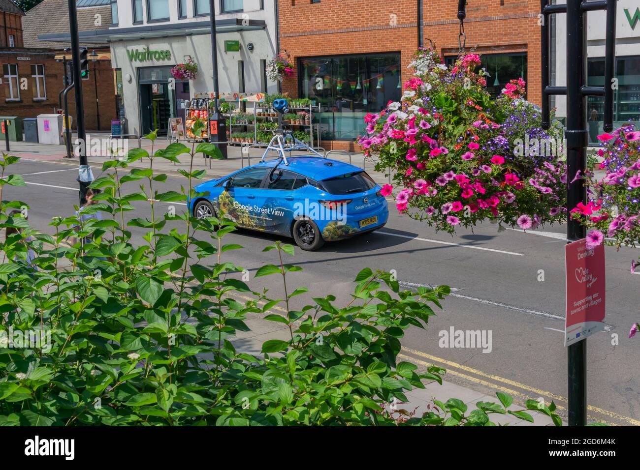 Dorking, Surrey, UK, 11-08-2021: A Blue Google Street View Car with a Roof Top Camera, Passing a Local Waitrose Supermarket on a Dry Summers Day with Stock Photo