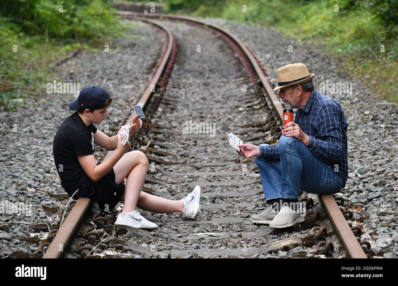 Man and boy playing cards on railway track Britain, Uk gamble gambling Stock Photo