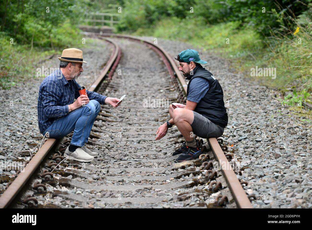Two men playing cards on railway track Britain, Uk gamble gambling Stock Photo
