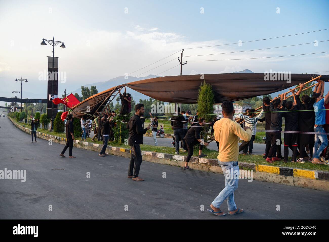 Srinagar, India. 11th Aug, 2021. Kashmiri Shia Muslims erect a 75 feet ...
