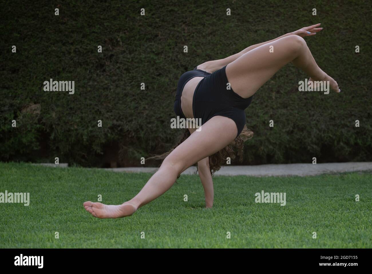 Unrecognized woman dancing modern dance on green grass. Practising dance outside. Stock Photo