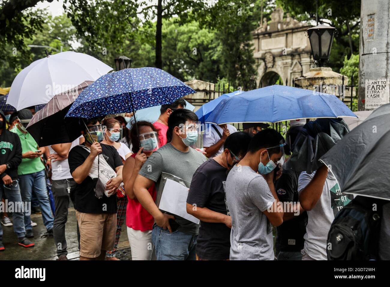 People wearing a protective mask and face shields queue to receive a shot of the AstraZeneca COVID-19 vaccine at the University of Santo Tomas. The university opened its vaccination site where about 1,000 doses of the AstraZeneca vaccine were administered by medical clerks and government health workers. Manila, Philippines. Stock Photo