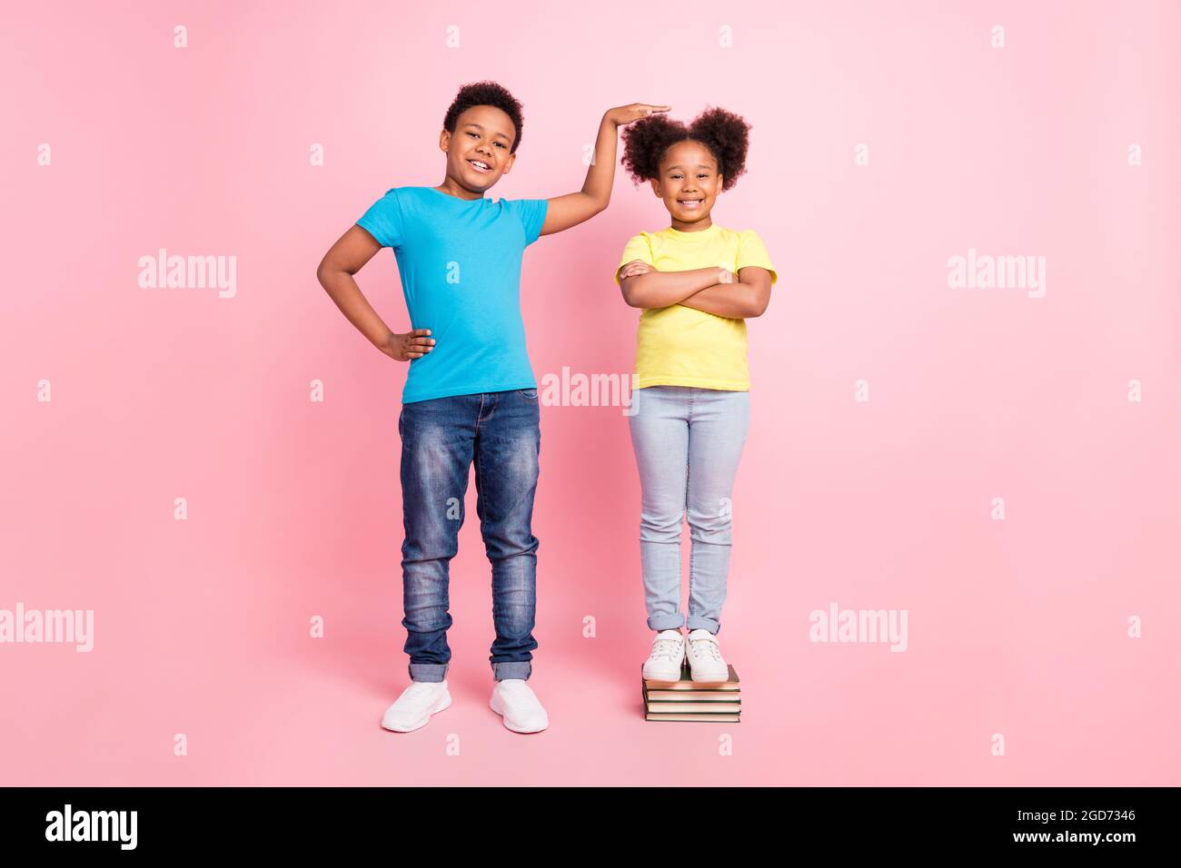 Full length body size view of two nice cheerful kids measuring height having fun isolated over pink pastel color background Stock Photo