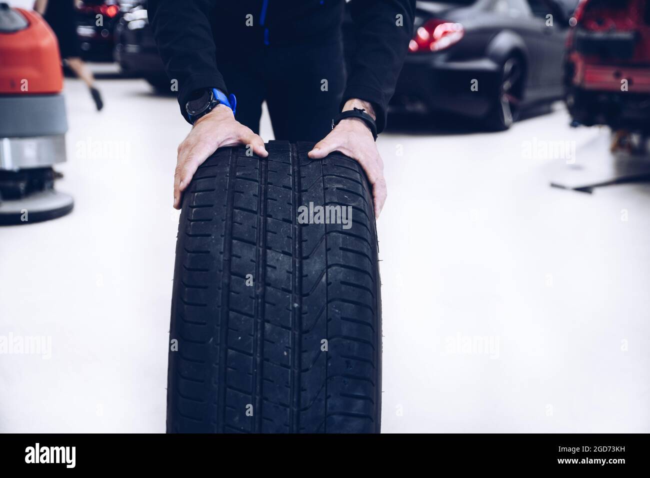 Mechanic holding car tire in seasonal tire change time Stock Photo Alamy