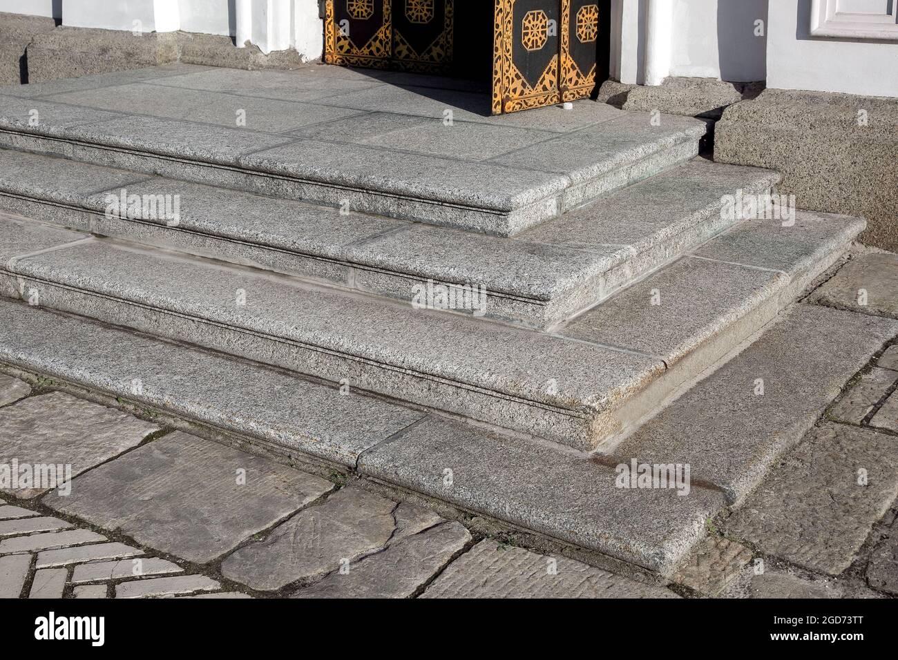 corner granite threshold at entrance open door made of black rust iron and white facade cladding of gray granite an old retro building close-up side v Stock Photo