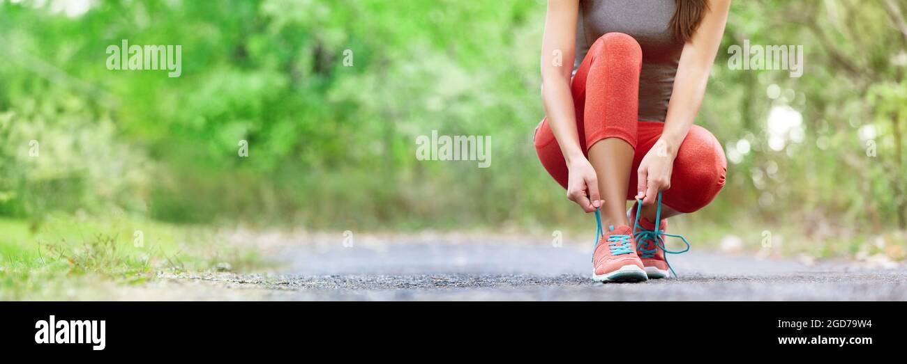 Exercise and sport running shoes runner woman tying laces getting ready for summer run in forest