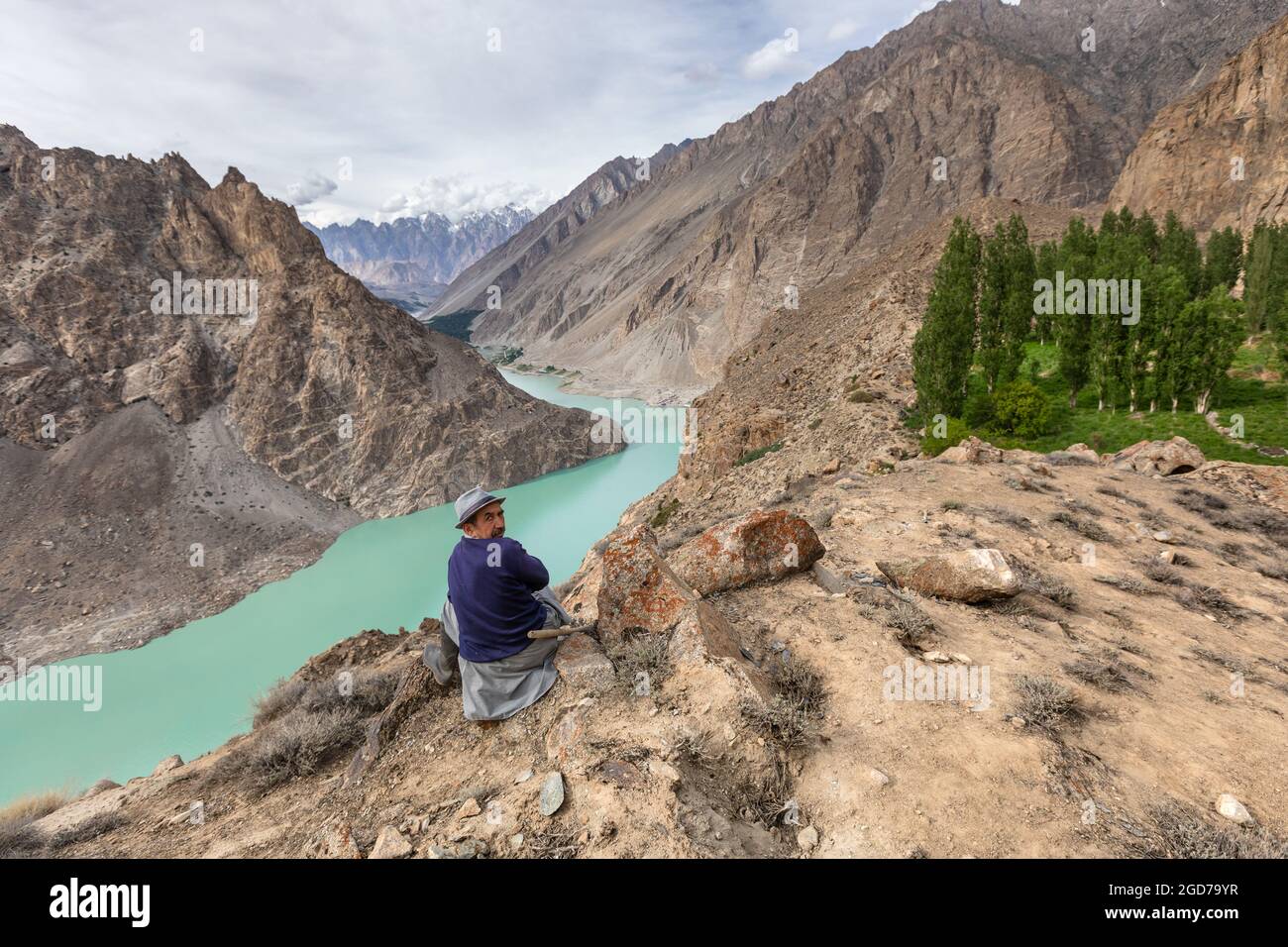 Hunza valley, Pakistan - June 2021:Man near turquoise mountain lake rocky shore Stock Photo