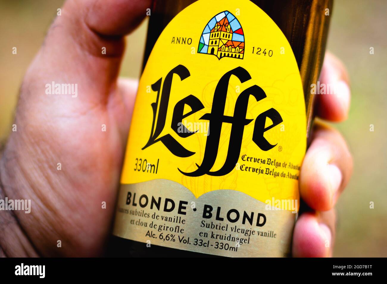 A man holds a Leffe beer bottle. It is a beer brand owned by InBev