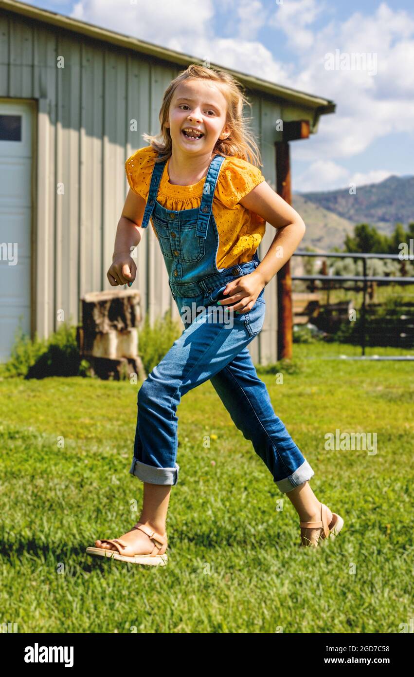 Young girl playing & running in grassy yard Stock Photo