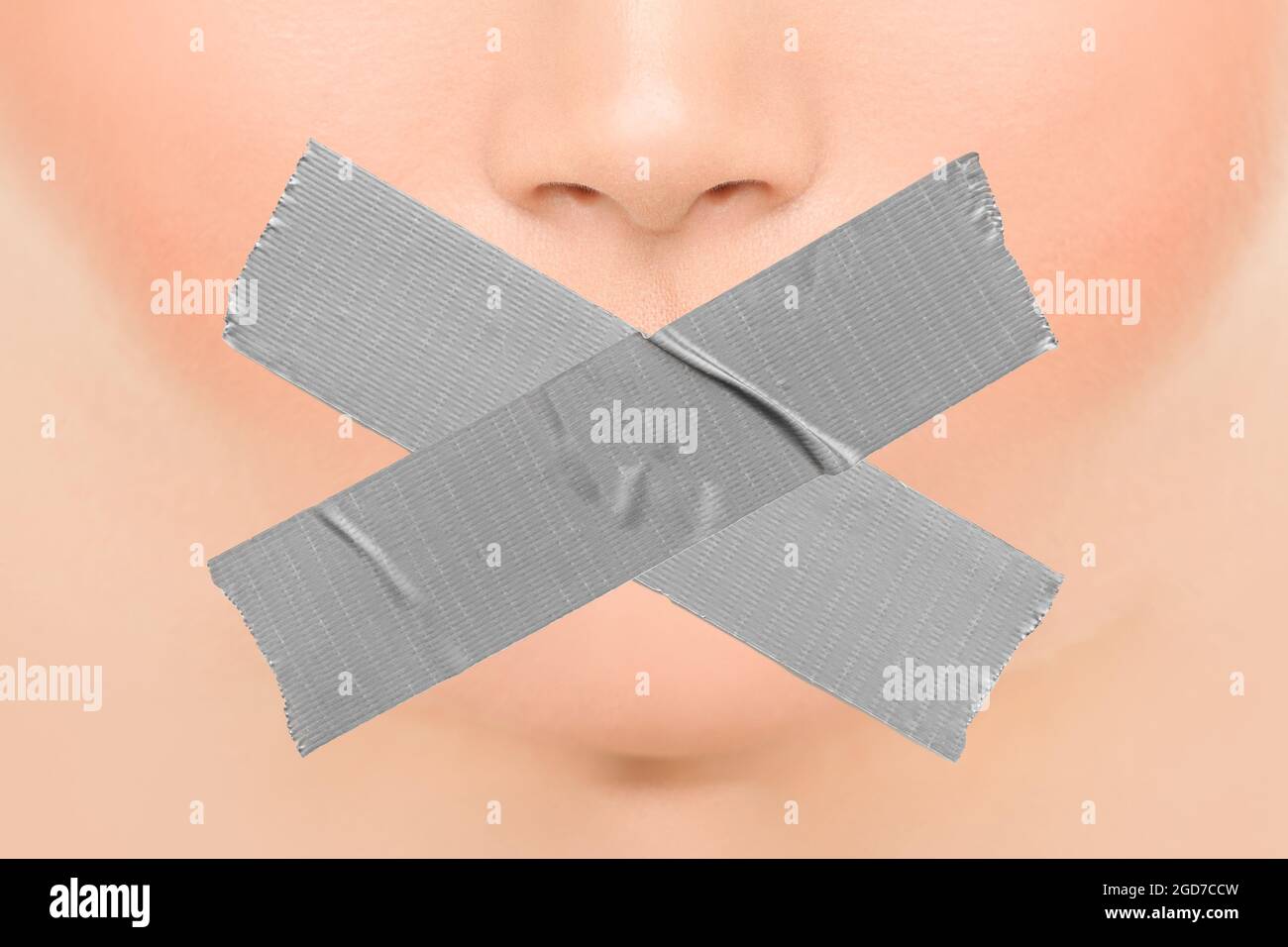 Woman silenced with adhesive duct tape covering closed mouth. Censorship, shut down of freedom of speech. Face nose and lips Stock Photo