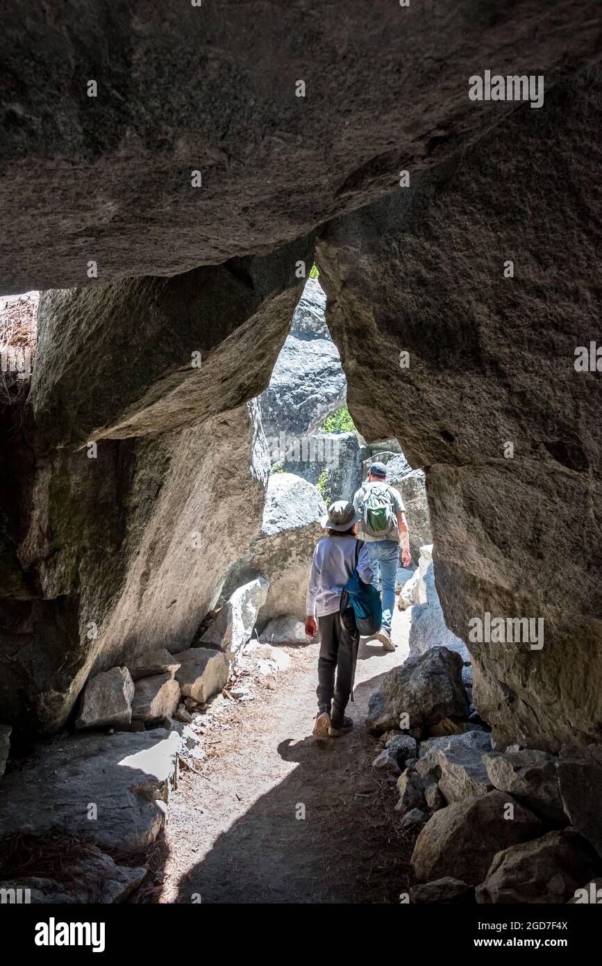 The River Trail takes hikers through a short tunnel of large granite boulders on their way toward Road's End in Kings Canyon National Park. Stock Photo