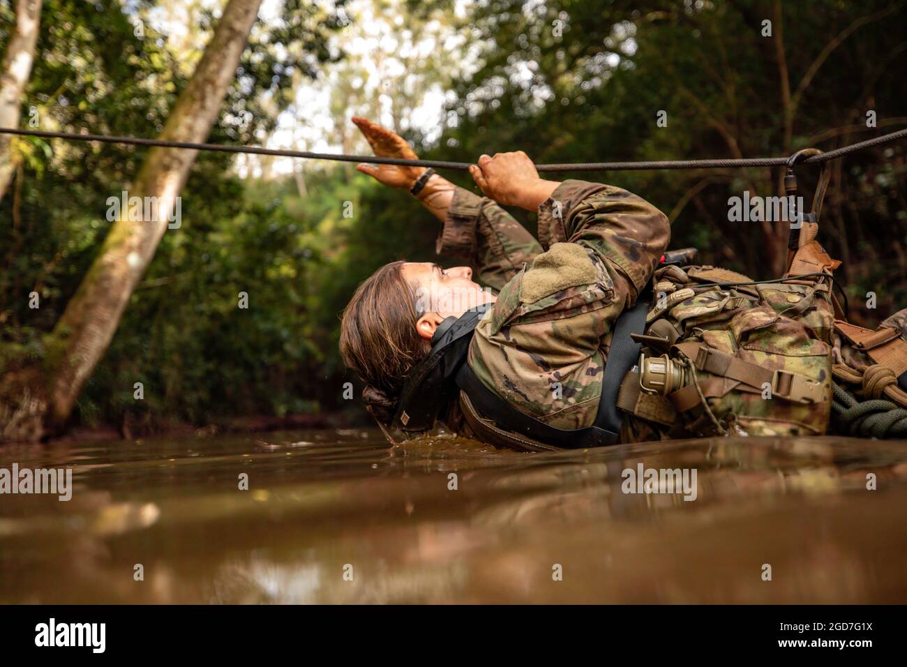 1st Lt. Brianne Hanley from 3rd Infantry Brigade Combat Team, 25th Infantry Division crosses a river with a one rope bridge during waterborne training on day six of Jungle Operations Training Course (JOTC) at East Range, Hawaii on Mar. 27, 2021. Senior leaders and Soldiers across the 25th Infantry Division attend JOTC in order to familiarize and certify themselves with jungle operation tactics, techniques, and procedures required to fight, win, and survive within any tropical jungle environment. (U.S. Army photo by 1st Lt. Angelo Mejia) Stock Photo