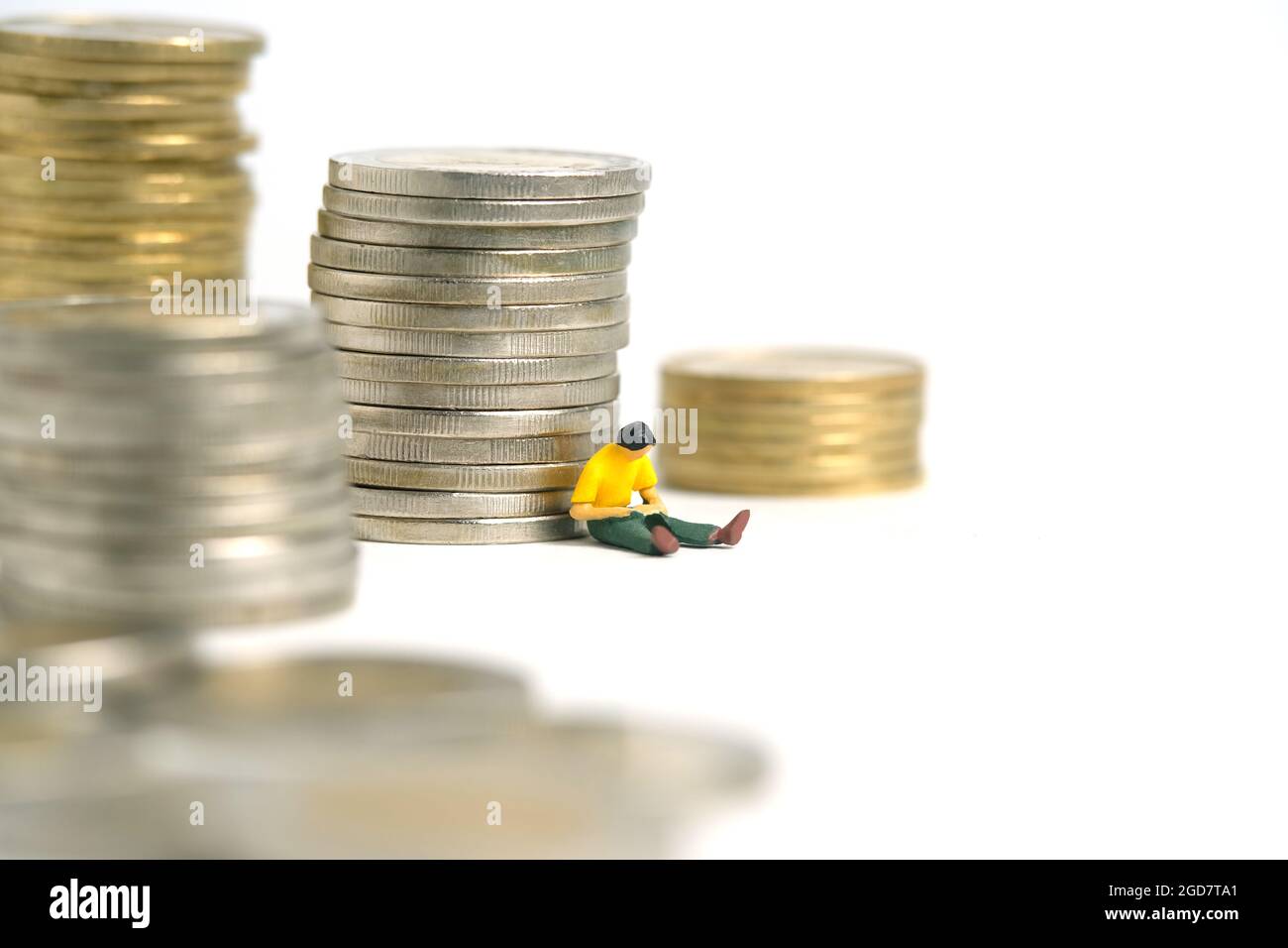 Miniature people toy figure photography. A men student sitting in front of money coin stack, isolated on white background. Image photo Stock Photo