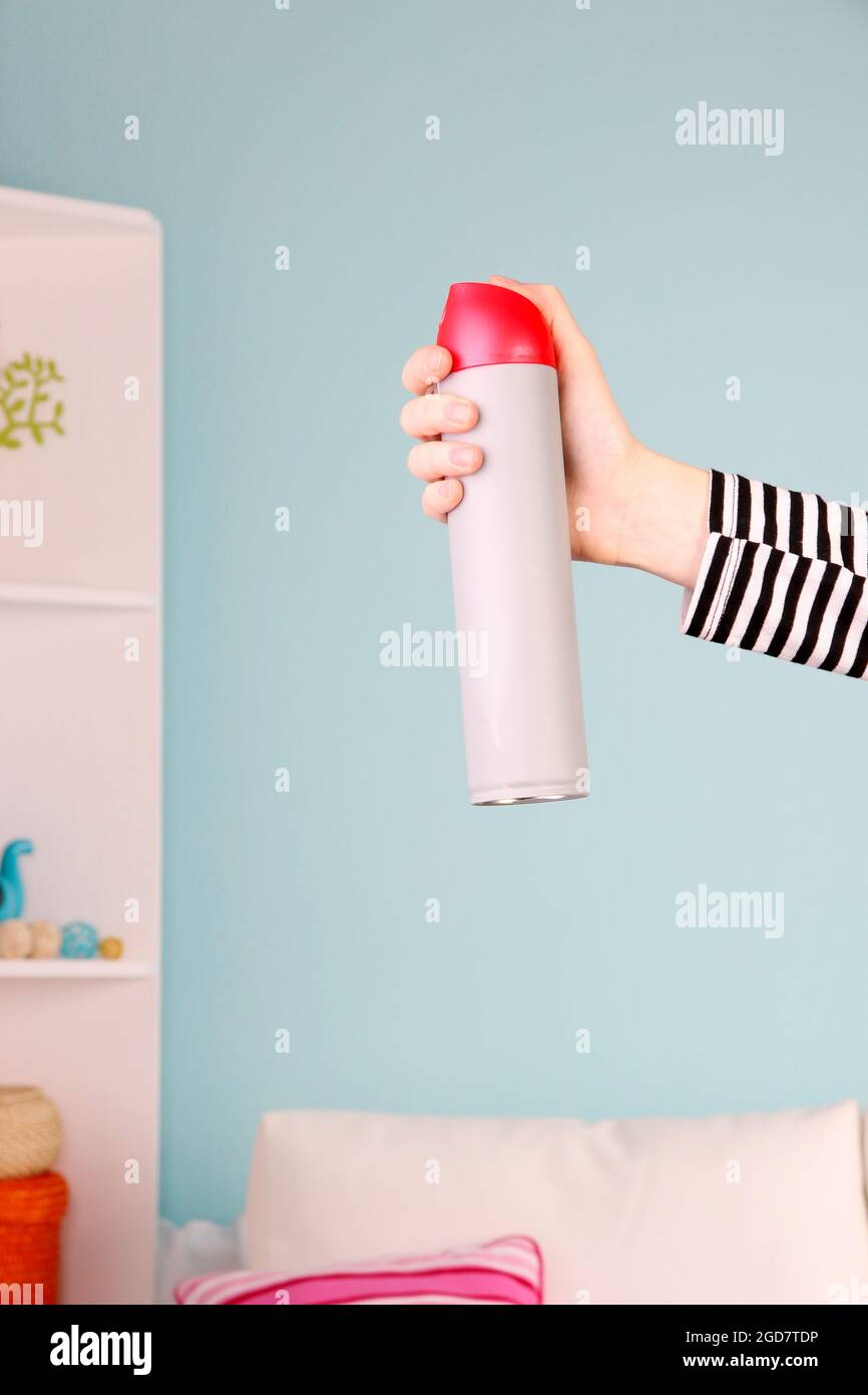 Sprayed air freshener in hand on home interior background Stock Photo