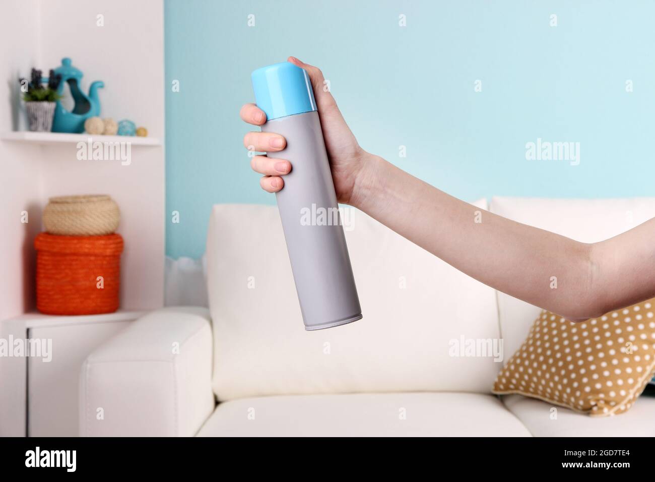 Sprayed air freshener in hand on home interior background Stock Photo