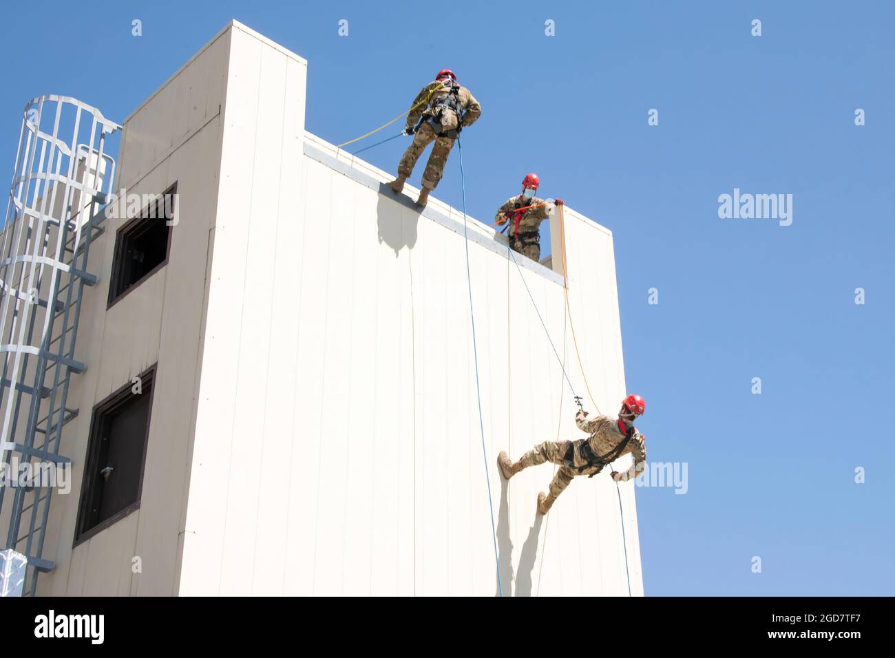 U.S. Air Force Staff Sgt. Justin Rice, center, 60th Civil Engineer Squadron lead firefighter, watches as Lt. Col. Matthew Suhre, right, 60th Mission Support Group deputy commander, and Staff Sgt. Daniel Robinson, 60th CES lead firefighter, rappel down a structure April 19, 2021, at the Travis Fire and Emergency Services training facility at Travis Air Force Base, California. The training demonstration provided senior leadership with a clear picture of the technical rescue capabilities for multi-story building and confined space rescues conducted by Travis AFB emergency response personnel. (U.S Stock Photo