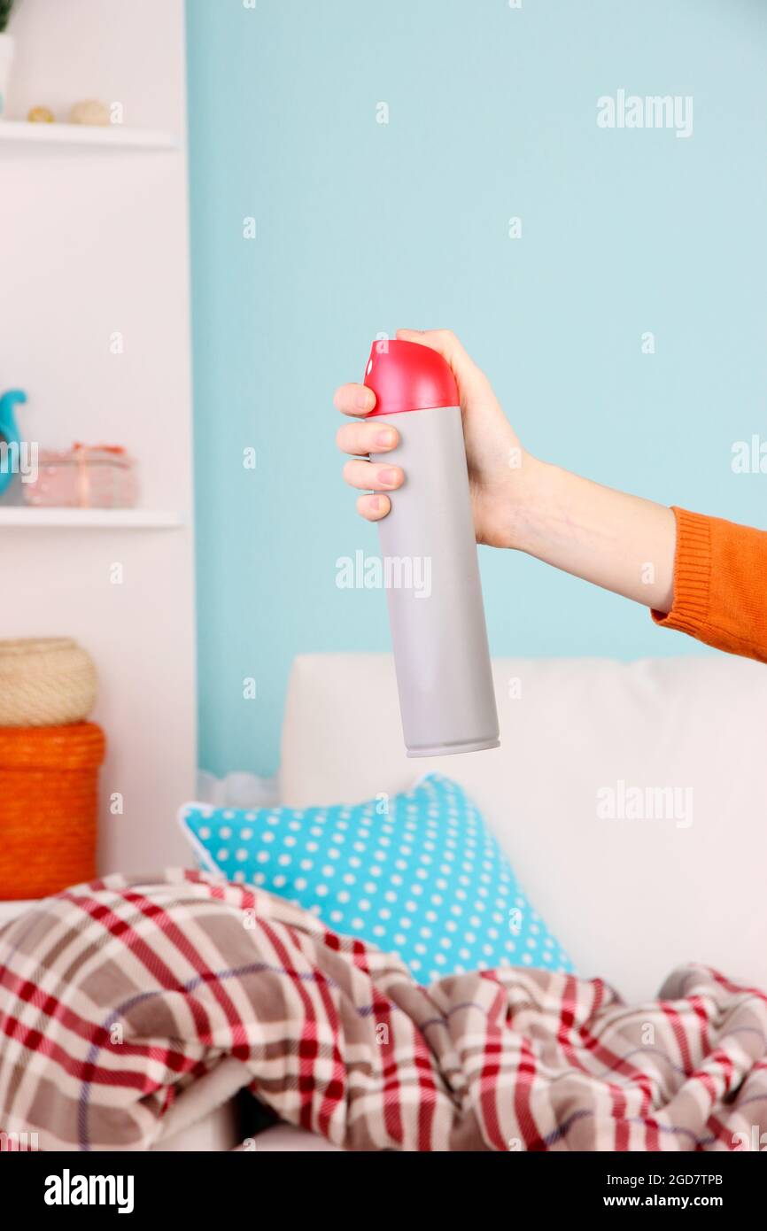 Sprayed air freshener in hand on home interior background Stock Photo