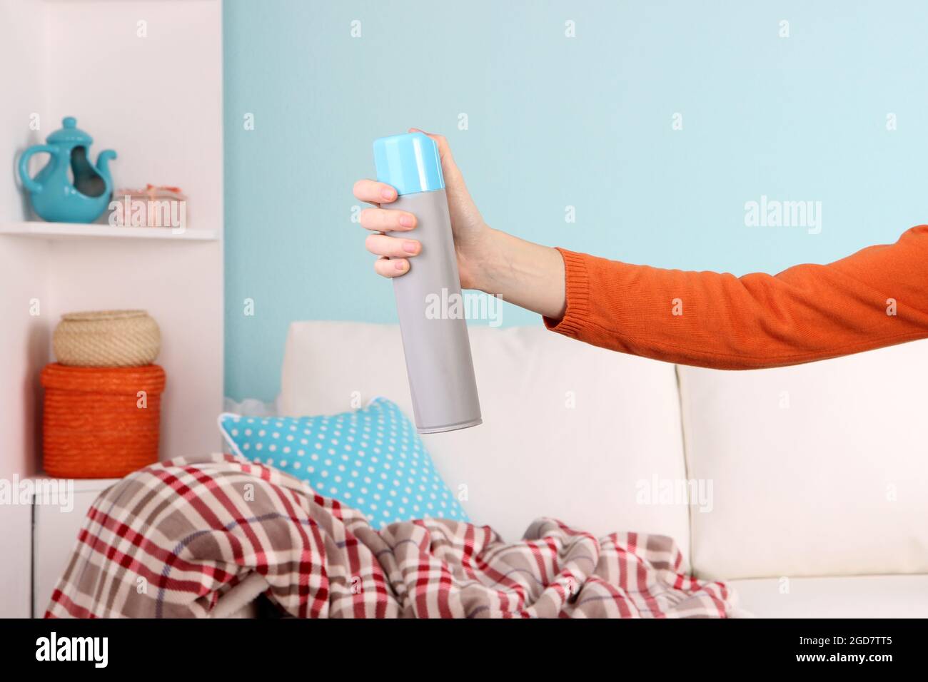 Sprayed air freshener in hand on home interior background Stock Photo