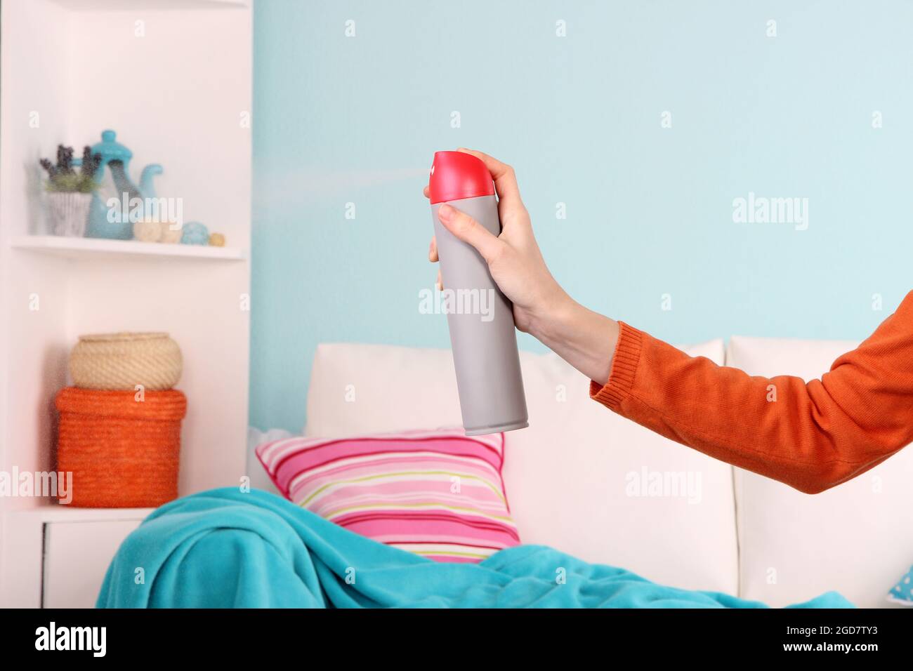 Sprayed air freshener in hand on home interior background Stock Photo