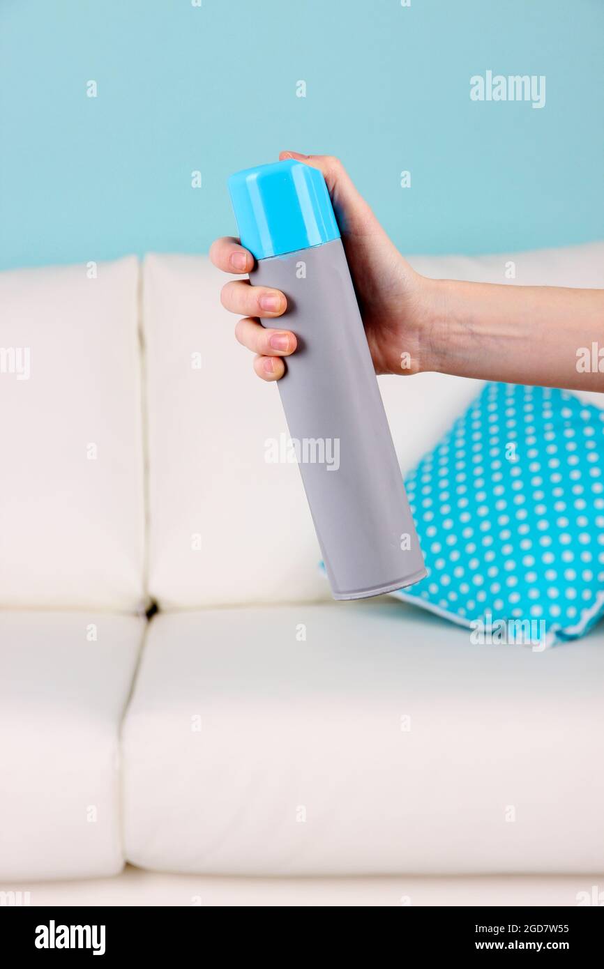 Sprayed air freshener in hand on home interior background Stock Photo