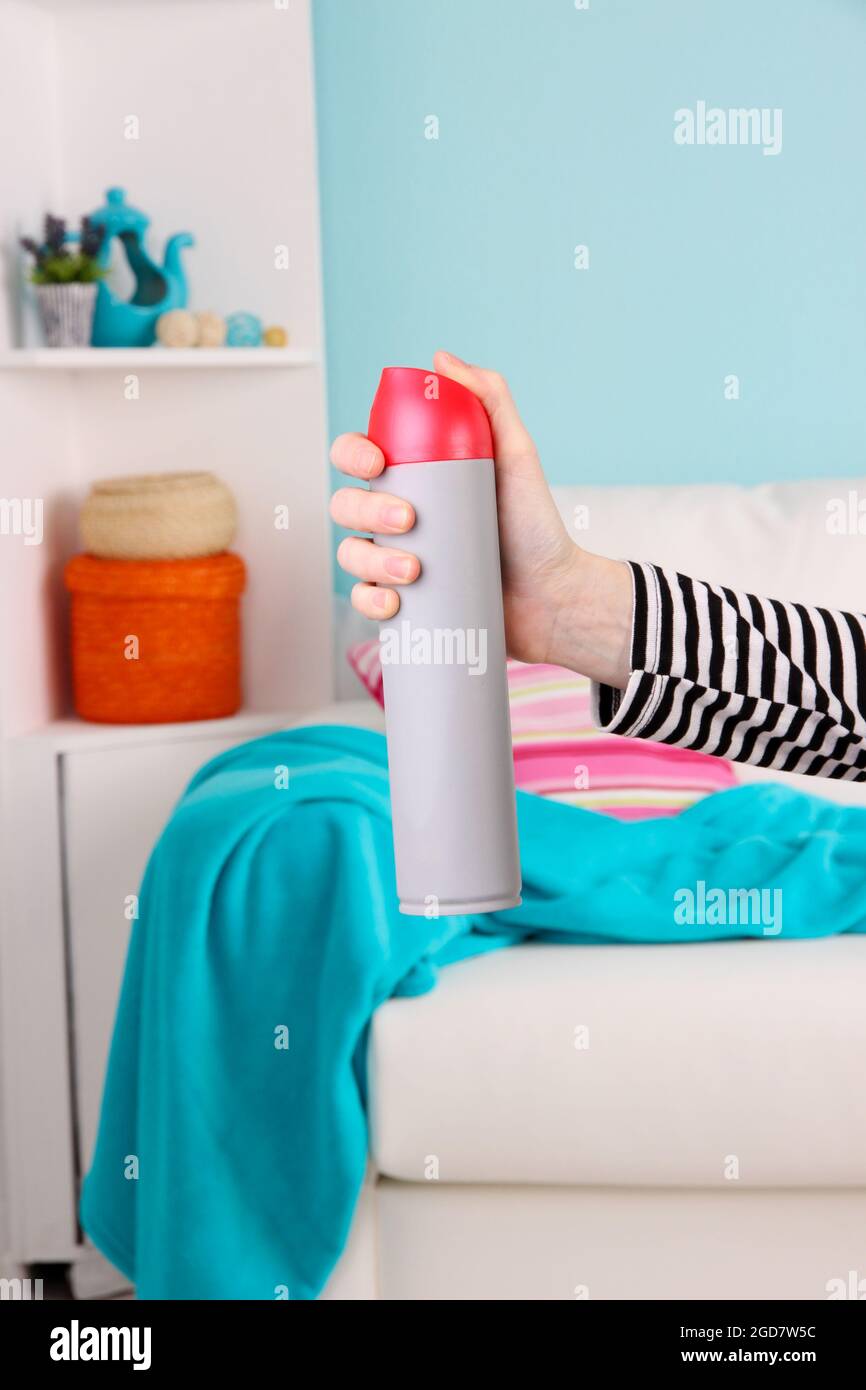 Sprayed air freshener in hand on home interior background Stock Photo