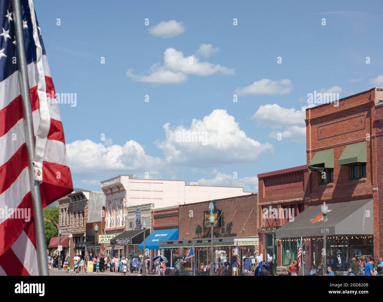 Main Street of Cody, Wyoming, during the Fourth of July celebration. USA flag in the foreground. Stock Photo
