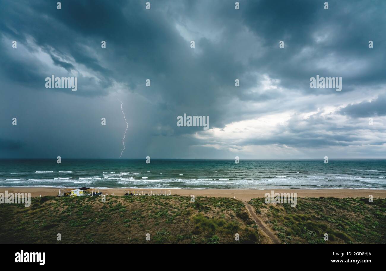 Lightning flash and dark thunderstorm over the ocean along the Mediterranean coast in Daimus, Spain Stock Photo