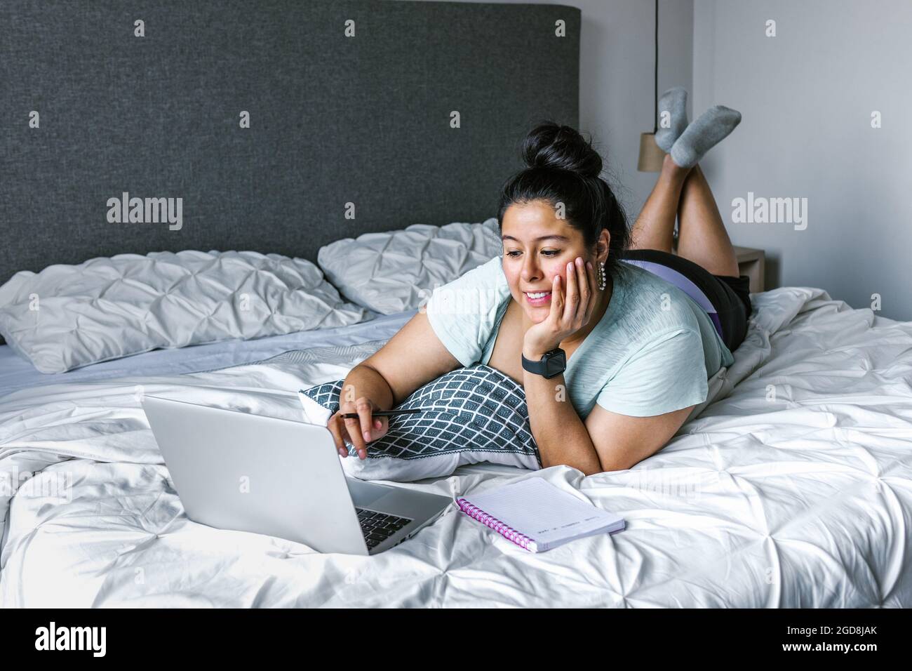 Curvy latin woman lying on bed using computer in Latin America, plus size  female Stock Photo - Alamy