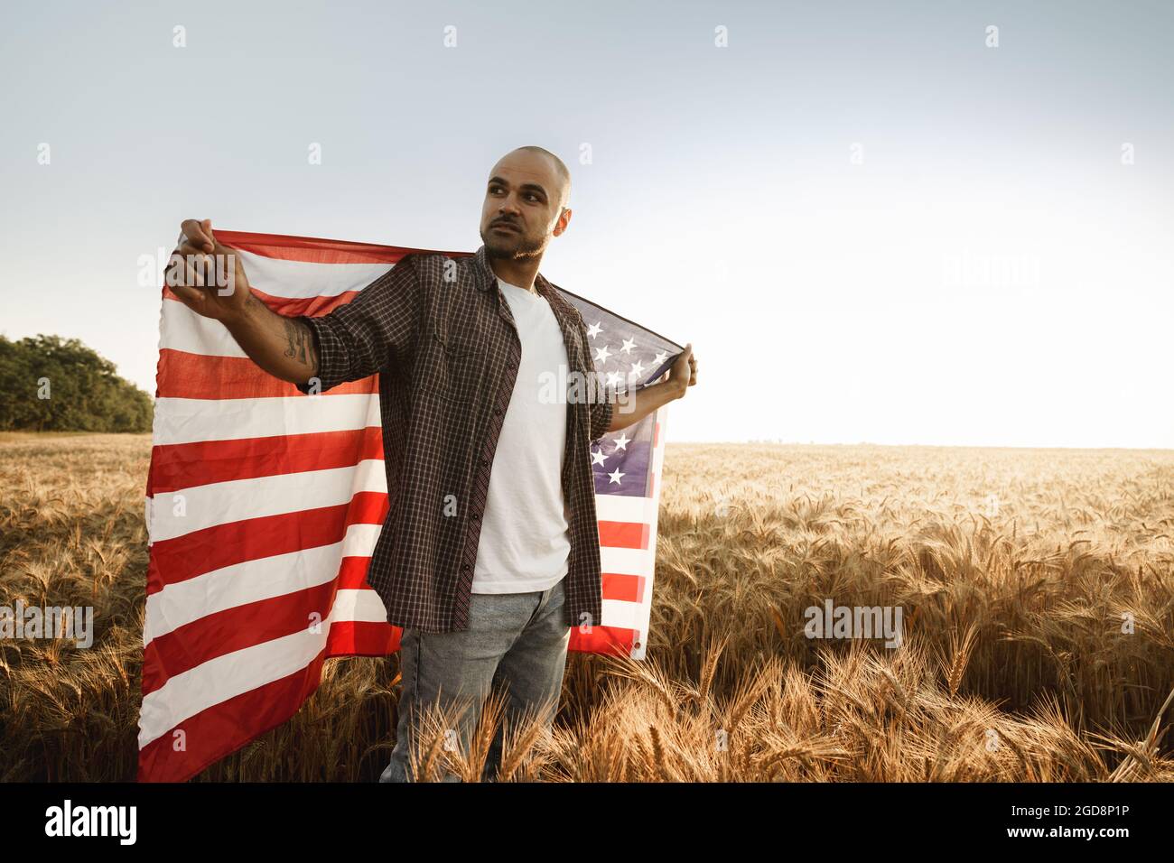 African american young man holding USA national flag through wheat ...