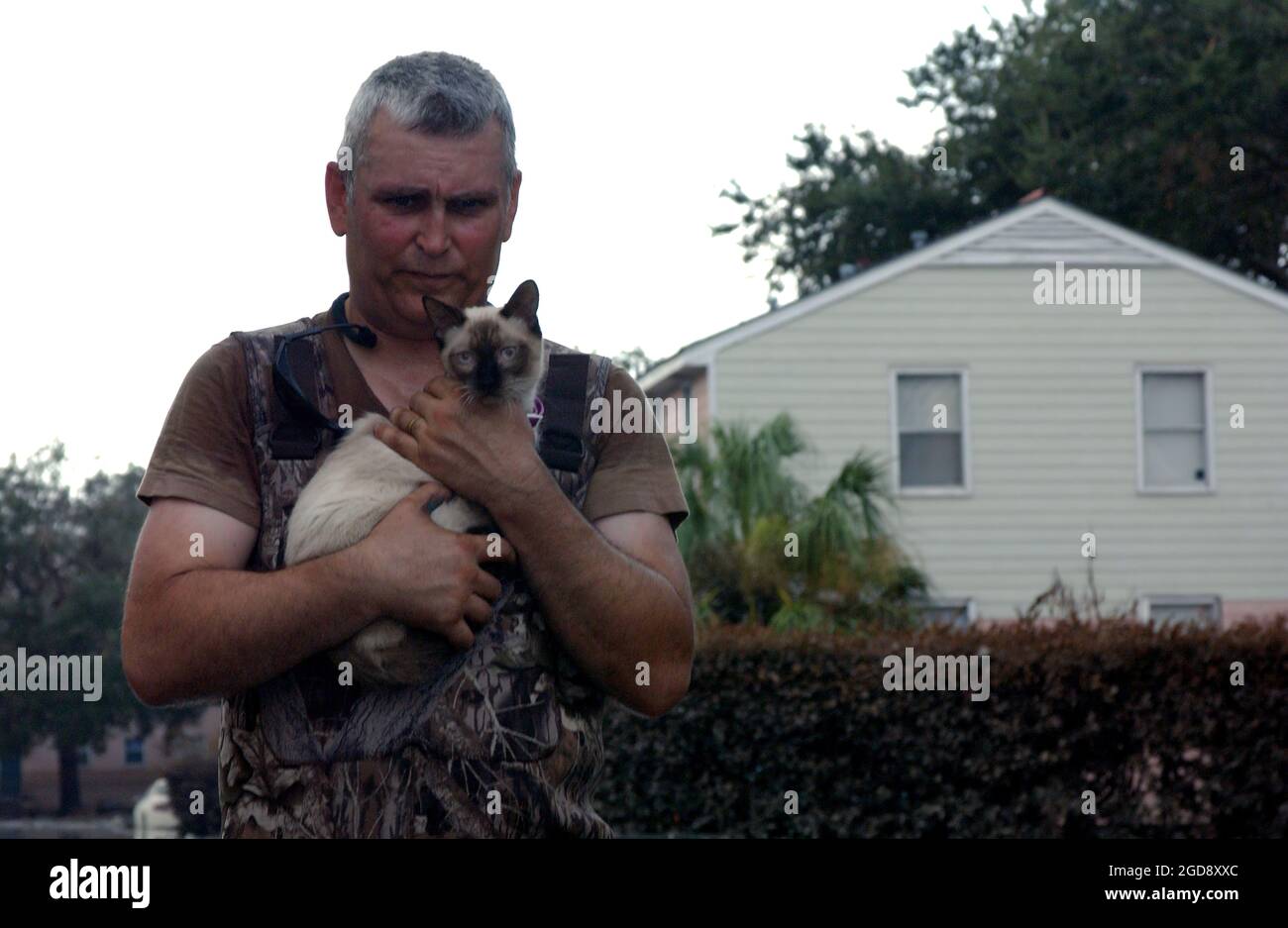 US Army (USA) Staff Sergeant (SSG) Charles Essler, 41st Brigade (BDE), Oregon Army National Guard (ORARNG), carries a Siamese cat he rescued from an apartment building in north New Orleans, Louisiana (LA), during a door-to-door external search as part of Joint Task Force (JTF) Hurricane Katrina. (USAF PHOTO BY TSGT ROGER M. DEY 050915-F-4970D-195) Stock Photo