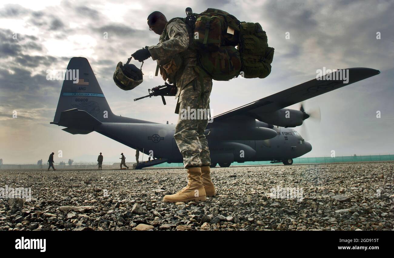 US Army (USA) Sergeant First Class (SFC) Ricky Bryant, carries his helmet, weapon and field pack, as he prepares to board a US Air Force (USAF) C-130 Hercules aircraft assigned to the 185th Airlift Squadron (AS), Oklahoma Air National Guard (OKANG) deployed to the 774th Expeditionary Airlift Squadron (EAS), during an operational re-supply mission conducted on a dirt air strip at Forward Operating Base (FOB) Salerno, Afghanistan, during Operation ENDURING FREEDOM.  (USAF PHOTO BY MSGT LANCE CHEUNG 060308-F-2907C-395) Stock Photo