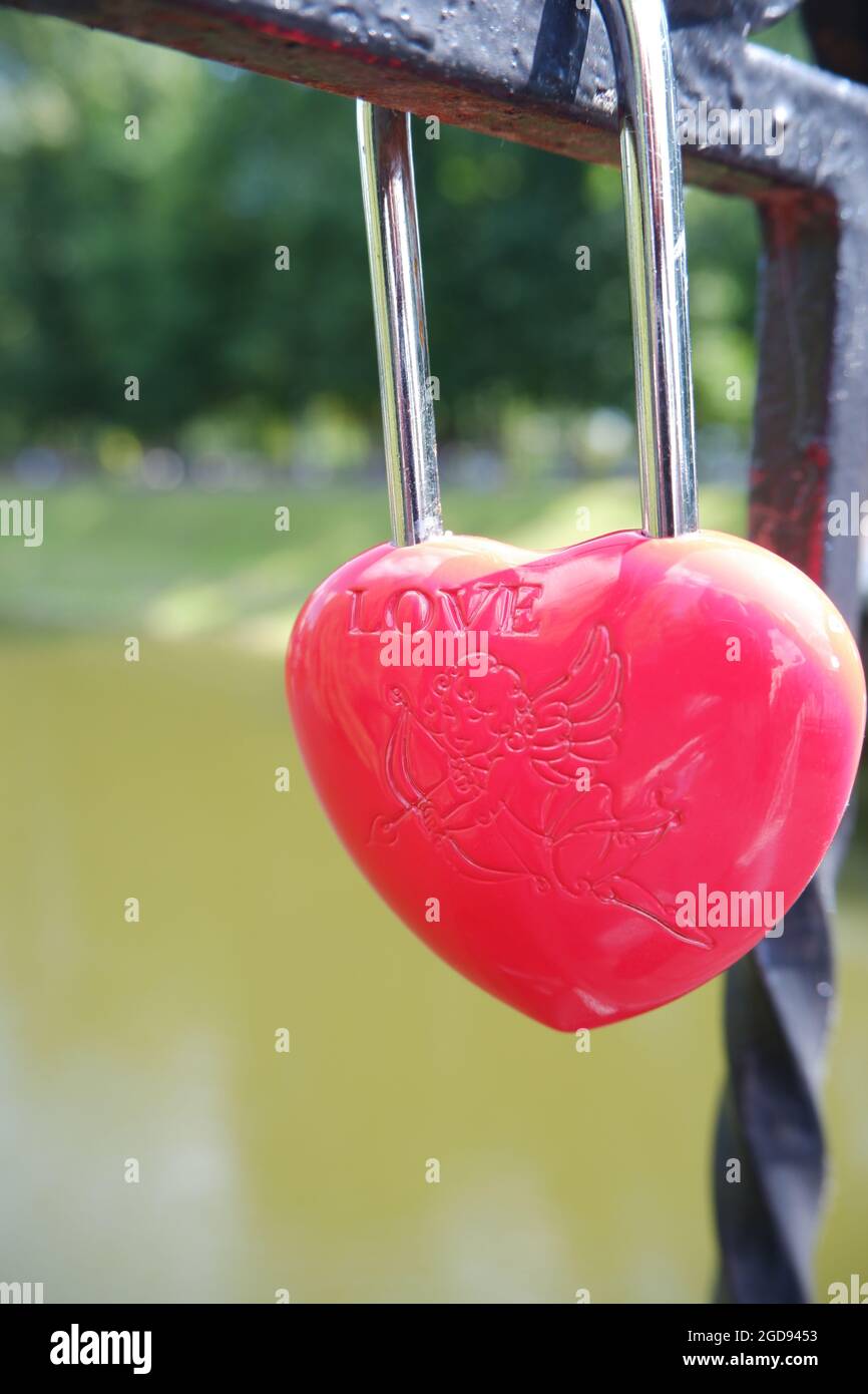Metal red door lock in the shape of a heart on the fence as a symbol of ...