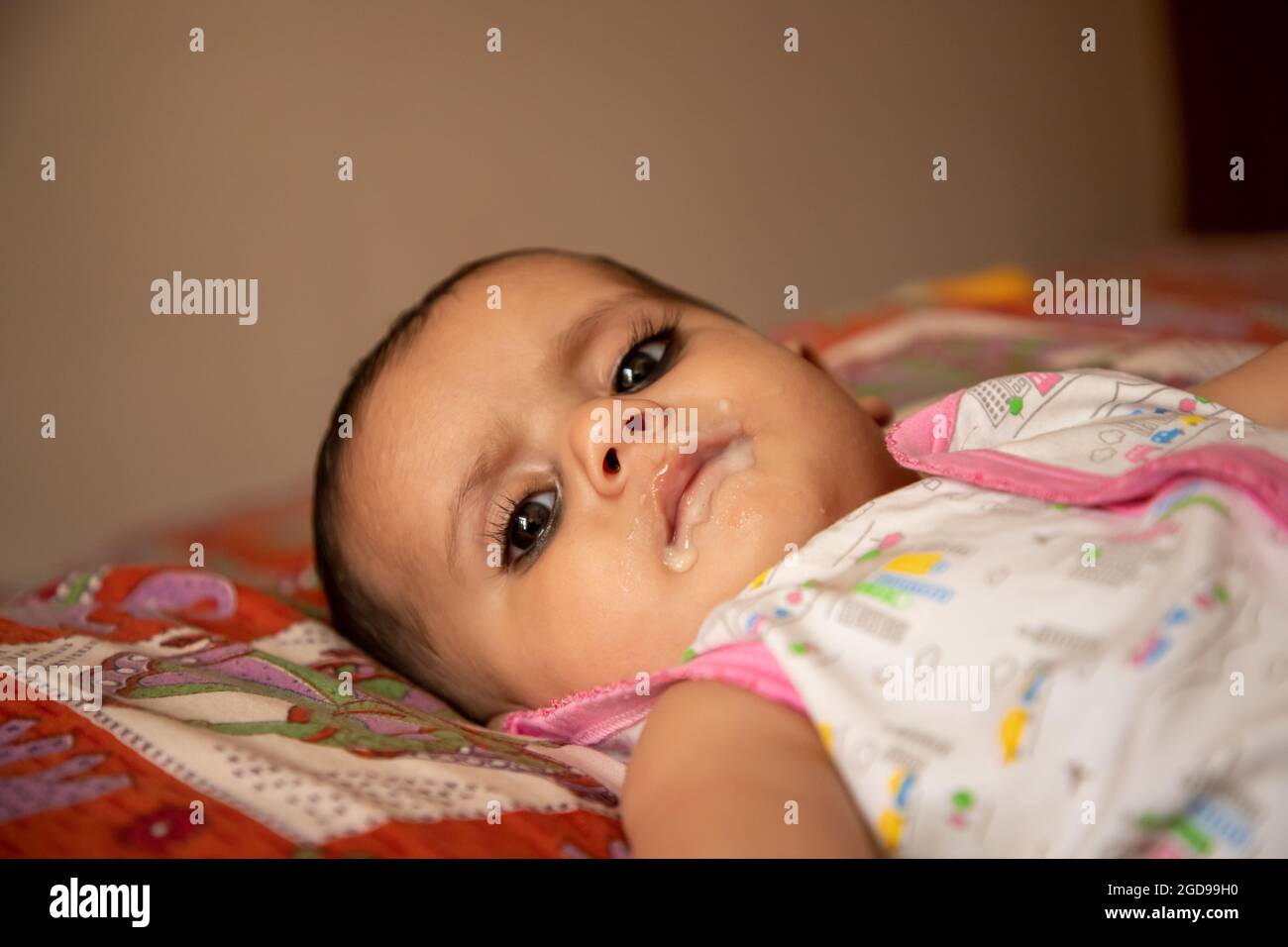 portrait of a adorable infant indian baby girl eating porridge with spoon. Stock Photo
