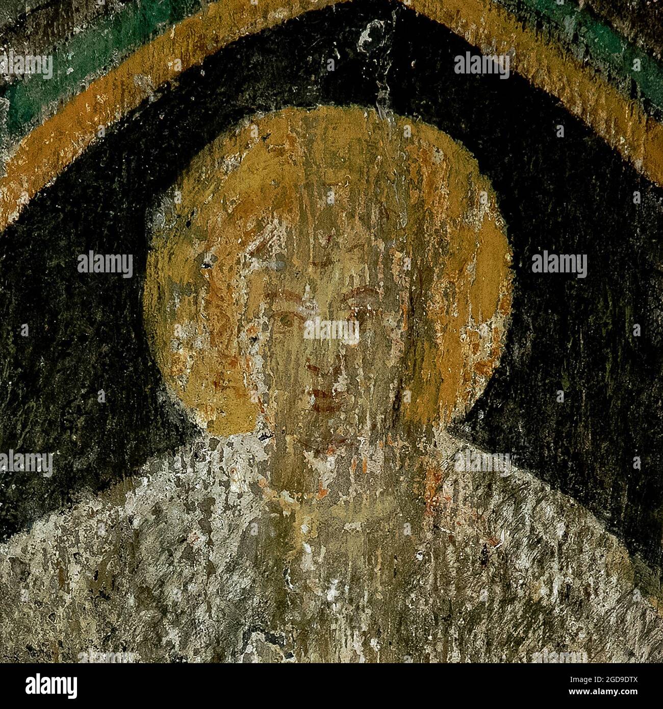 Square portrait of an angel, a faded fresco face painted in about 1400 on the underside of a rounded Romanesque window arch in the Blasiuskapelle or Chapel of Saint Blaise in the Burggarten or Castle Garden at Rothenburg ob der Tauber, Bavaria, Germany.   The fresco was painted when the chapel was formed from a remnant, probably a reception hall, of the Hohenstaufen imperial fortress built by Konrad III, King of Germany.  The rest of the castle was destroyed by the Basel earthquake of 1356.  The chapel is now a memorial to the military dead of two world wars. Stock Photo