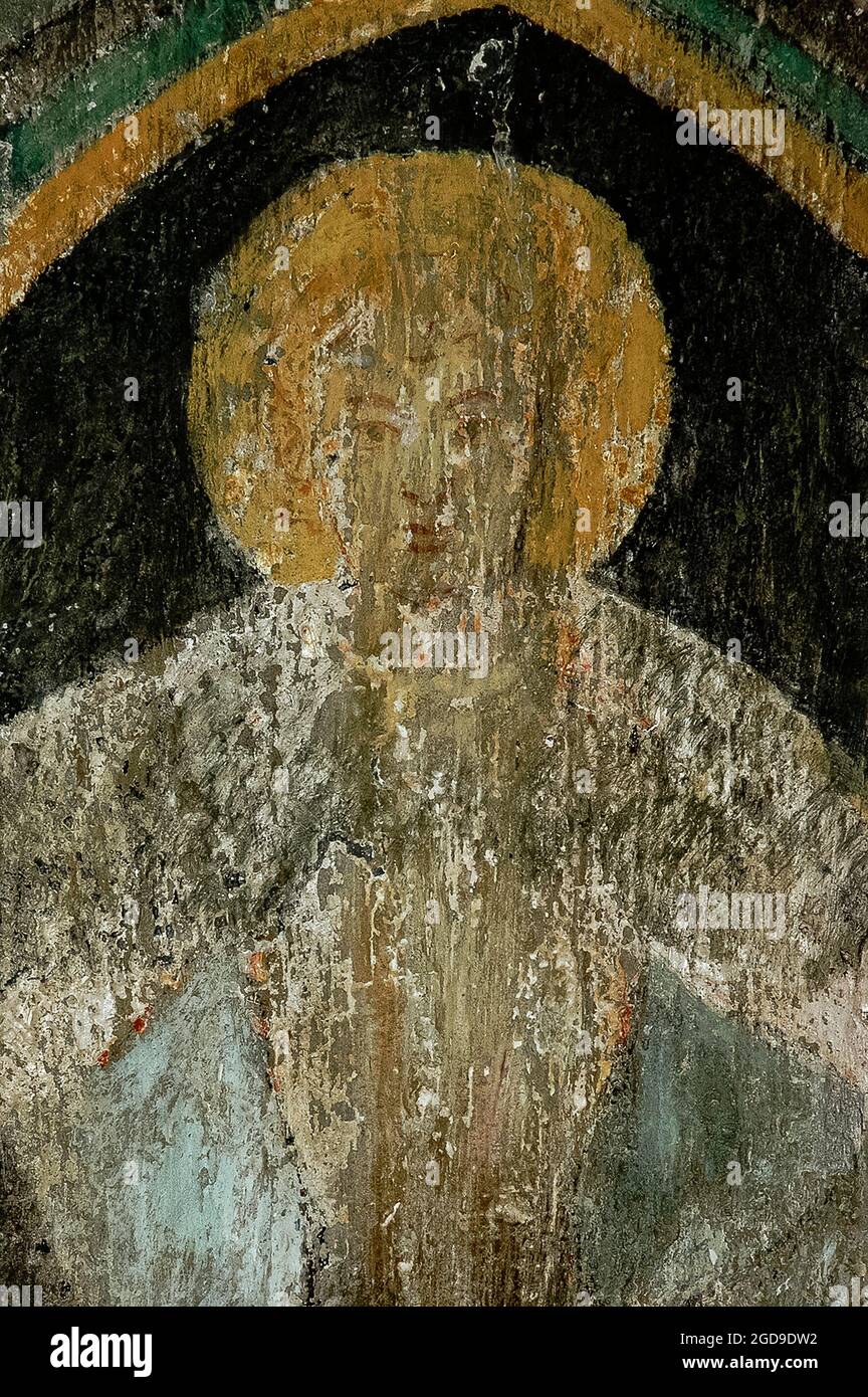 The face of an angel in faded fresco art painted in about 1400 on the underside of a rounded Romanesque window arch in the Blasiuskapelle or Chapel of Saint Blaise in the Burggarten or Castle Garden at Rothenburg ob der Tauber, Bavaria, Germany.   The fresco was painted when the chapel was formed from a remnant, probably a reception hall, of the Hohenstaufen imperial fortress built by Konrad III, King of Germany.  The rest of the castle was destroyed by the Basel earthquake of 1356.  The chapel is now a memorial to the military dead of two world wars. Stock Photo