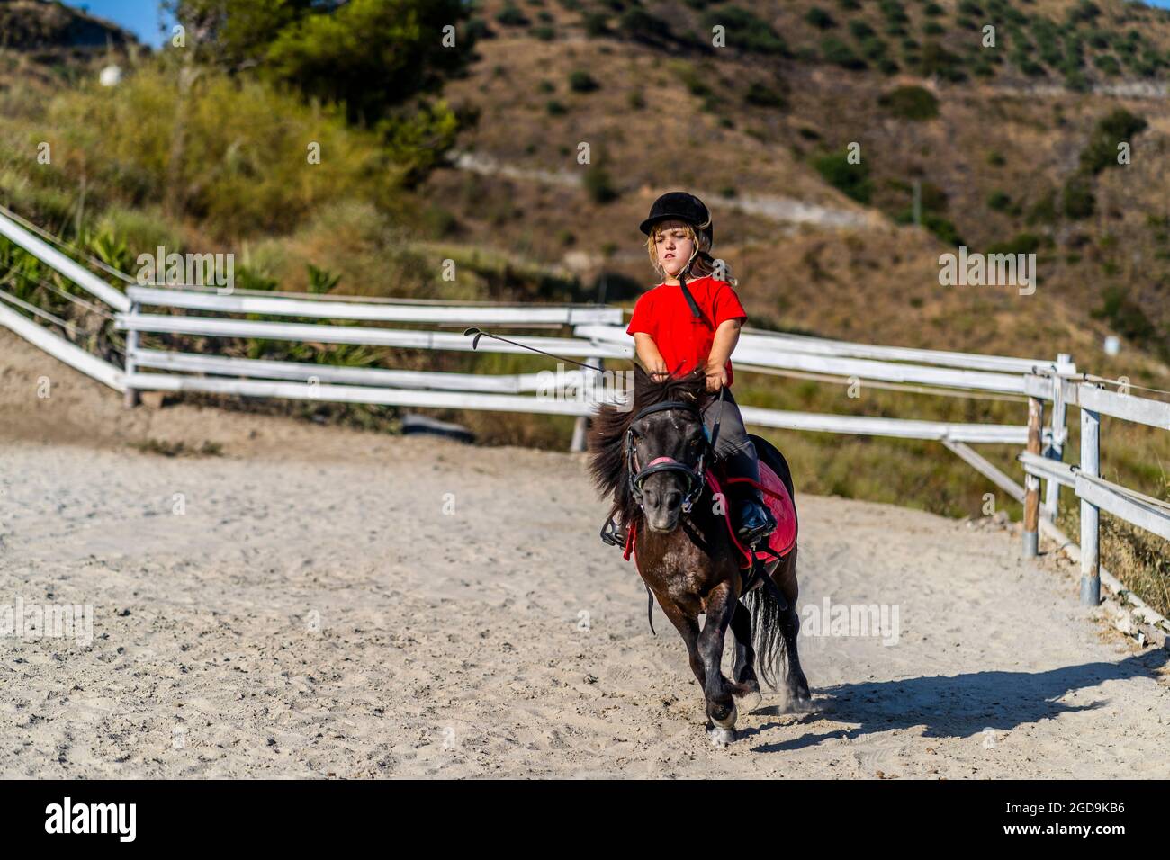 Nerja, Spain - July 14, 2021: Dwarf girl Anika brilliantly riding pony horse Stock Photo