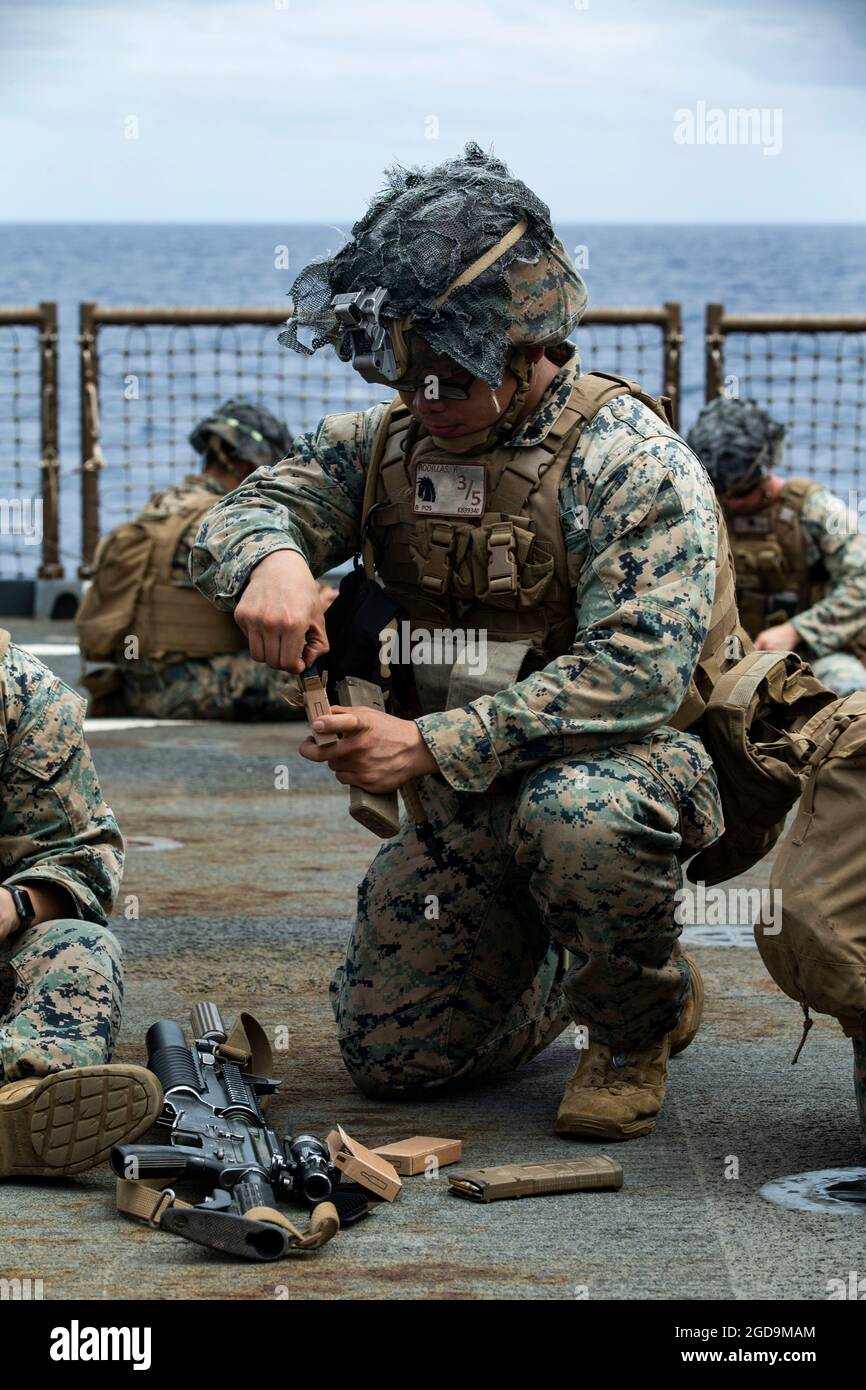 U.S. Marine Corps Cpl. Raven Rodillas, a rifleman with Battalion Landing Team 3/5, 31st Marine Expeditionary Unit (MEU) loads a magazine with live ammunition for a range aboard USS Germantown in the Solomon Sea, August 2, 2021. The range was created to challenge Marines with obstacles to increase tactical proficiency. The 31st MEU is operating aboard ships of the America Expeditionary Strike Group in the 7th fleet area of operations to enhance interoperability with allies and partners and serve as a ready response force to defend peace and stability in the Indo-Pacific region. (U.S. Marine Cor Stock Photo