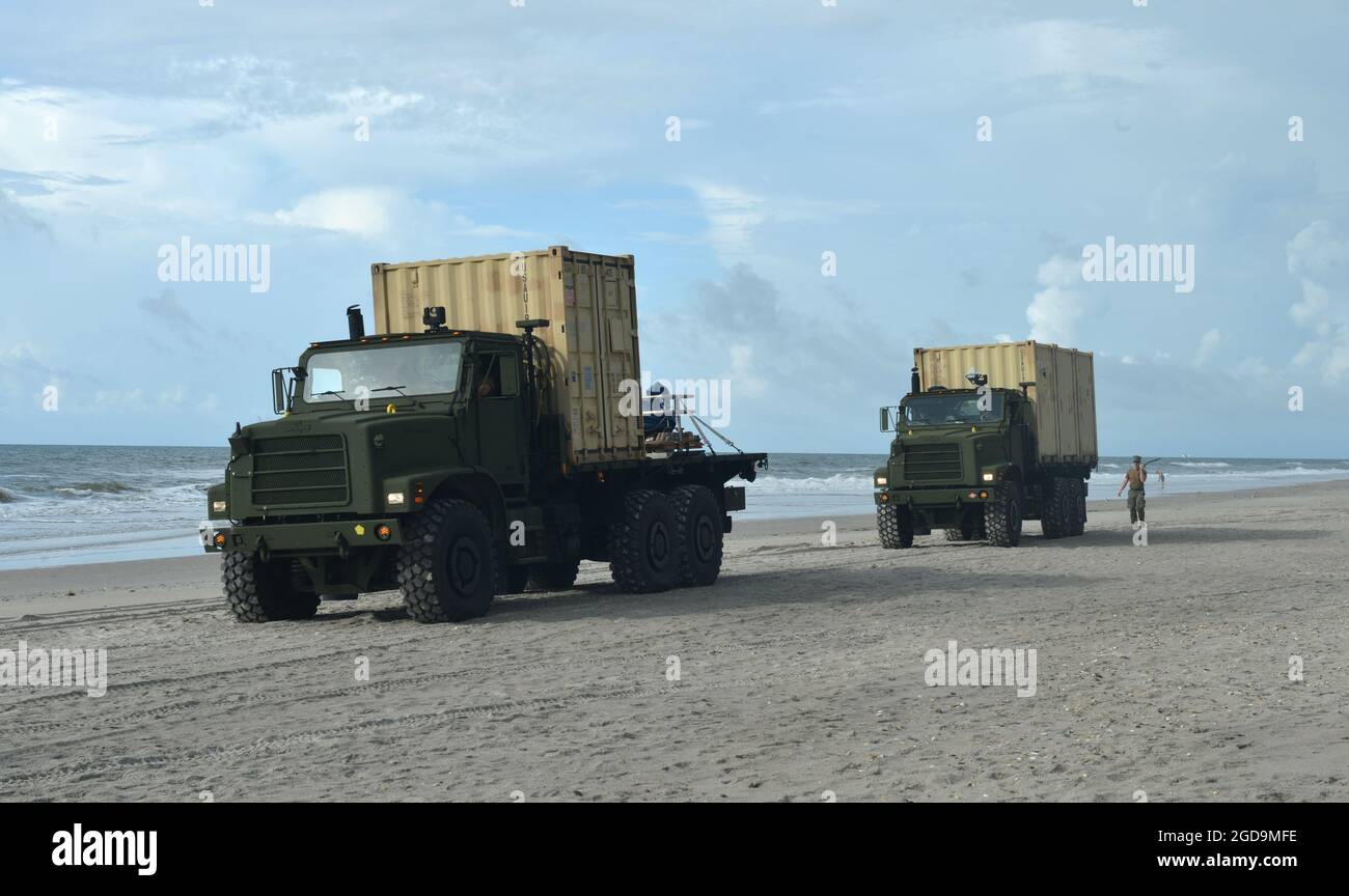 Sailors from Navy Cargo Handling Battalion ONE unload gear for the distributed littoral operational fuel transfer system (DLOFTS) on Onslow beach, N.C. as part of Large-Scale Exercise (LSE 2021), Aug. 7, 2021. LSE 2021 demonstrates the Navy’s ability to employ precise, lethal, and overwhelming force globally across three naval component commands, five numbered fleets, and 17 time zones. LSE 2021 merges live and synthetic training capabilities to create an intense, robust training environment. It will connect high-fidelity training and real-world operations, to build knowledge and skills needed Stock Photo