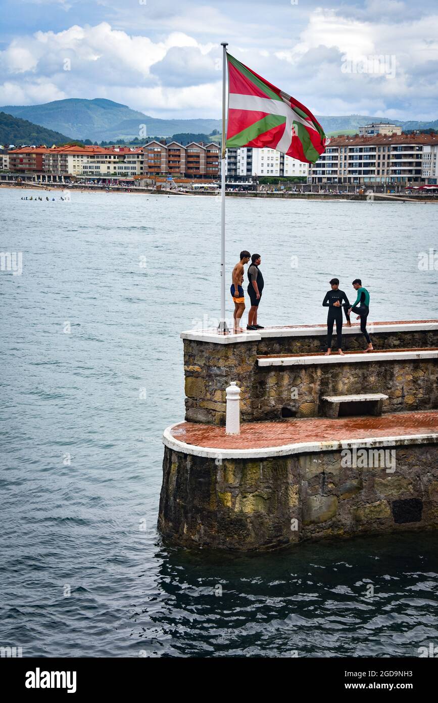 Zarautz, Spain - July 25, 2021:  Local teens jump into the sea from the harbour walls in the town of Zarautz in the Basque Country Stock Photo