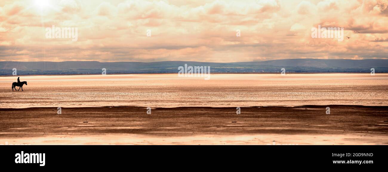 Horse rider on the beach at sunset, dramatic sky, sun and hills on the ...