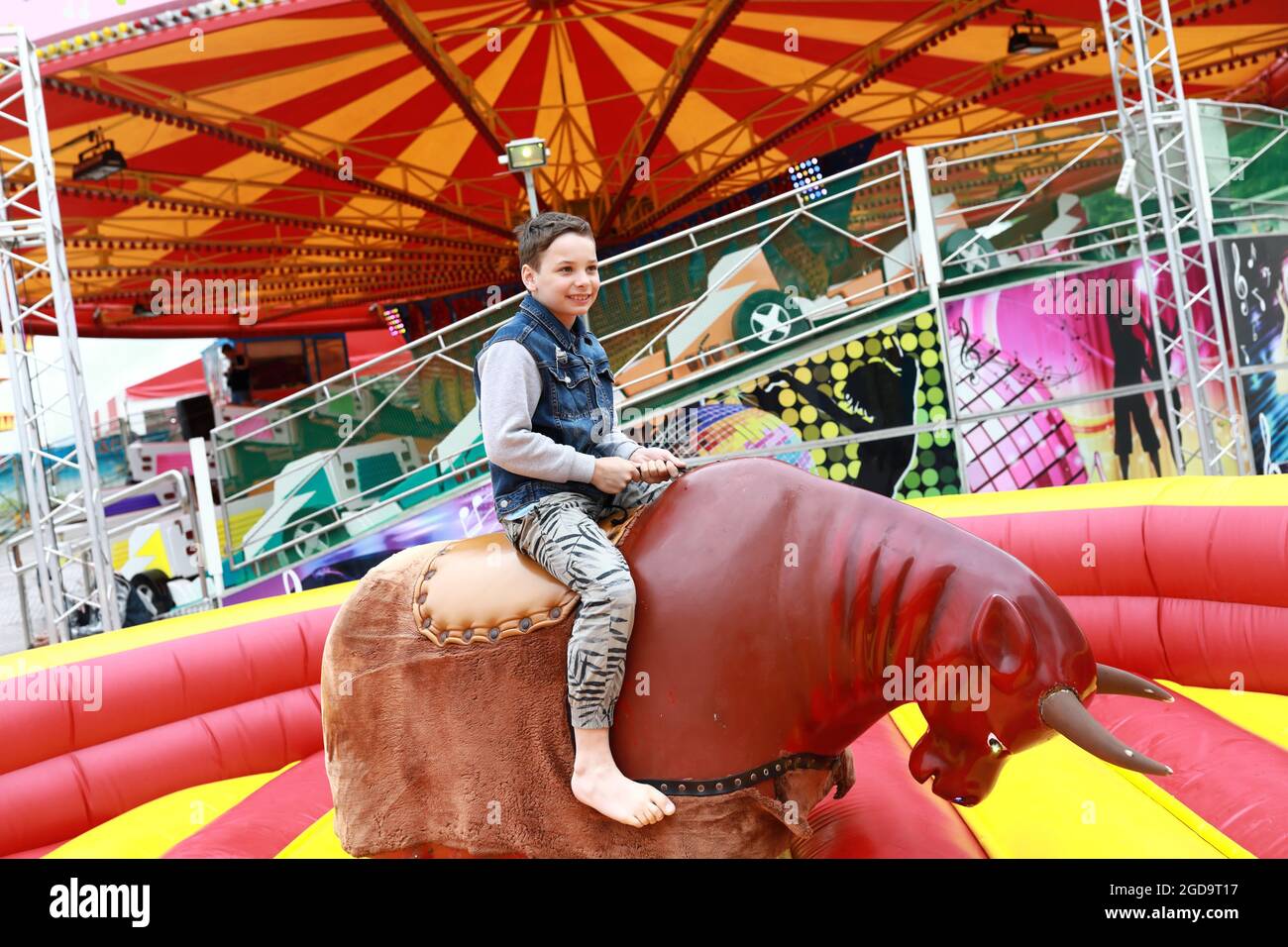 Child riding on mechanical bull in amusement park Stock Photo
