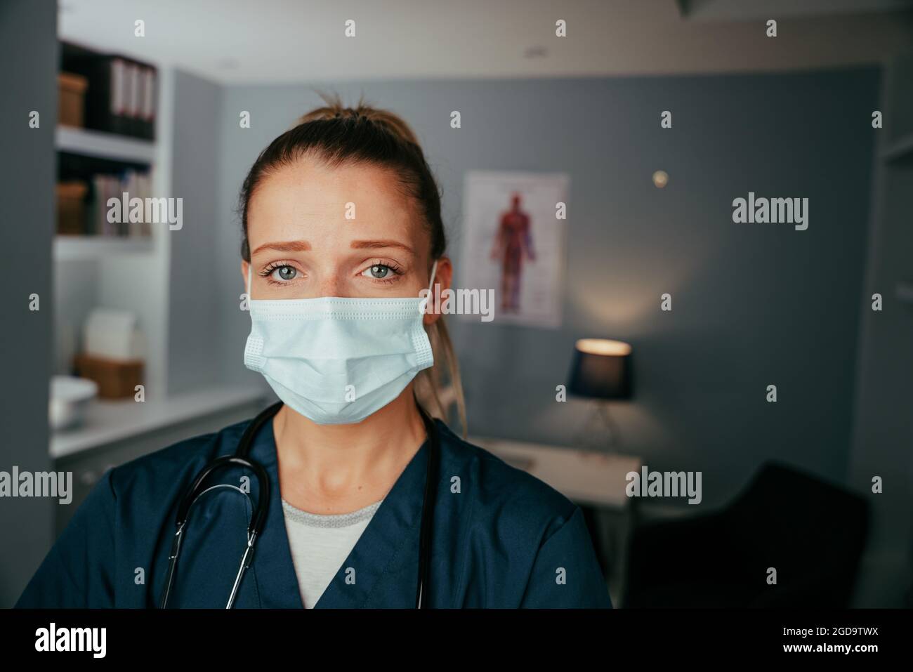 Caucasian female nurse standing in doctors office wearing surgical mask Stock Photo