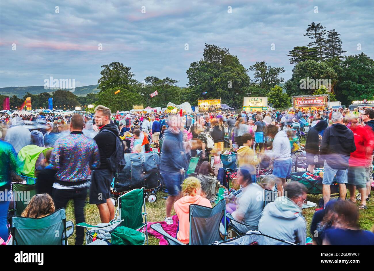 A dusk view of crowds of spectators in front of the main stage at Camp Bestival, a family-friendly annual music festival in Lulworth, Dorset, UK Stock Photo