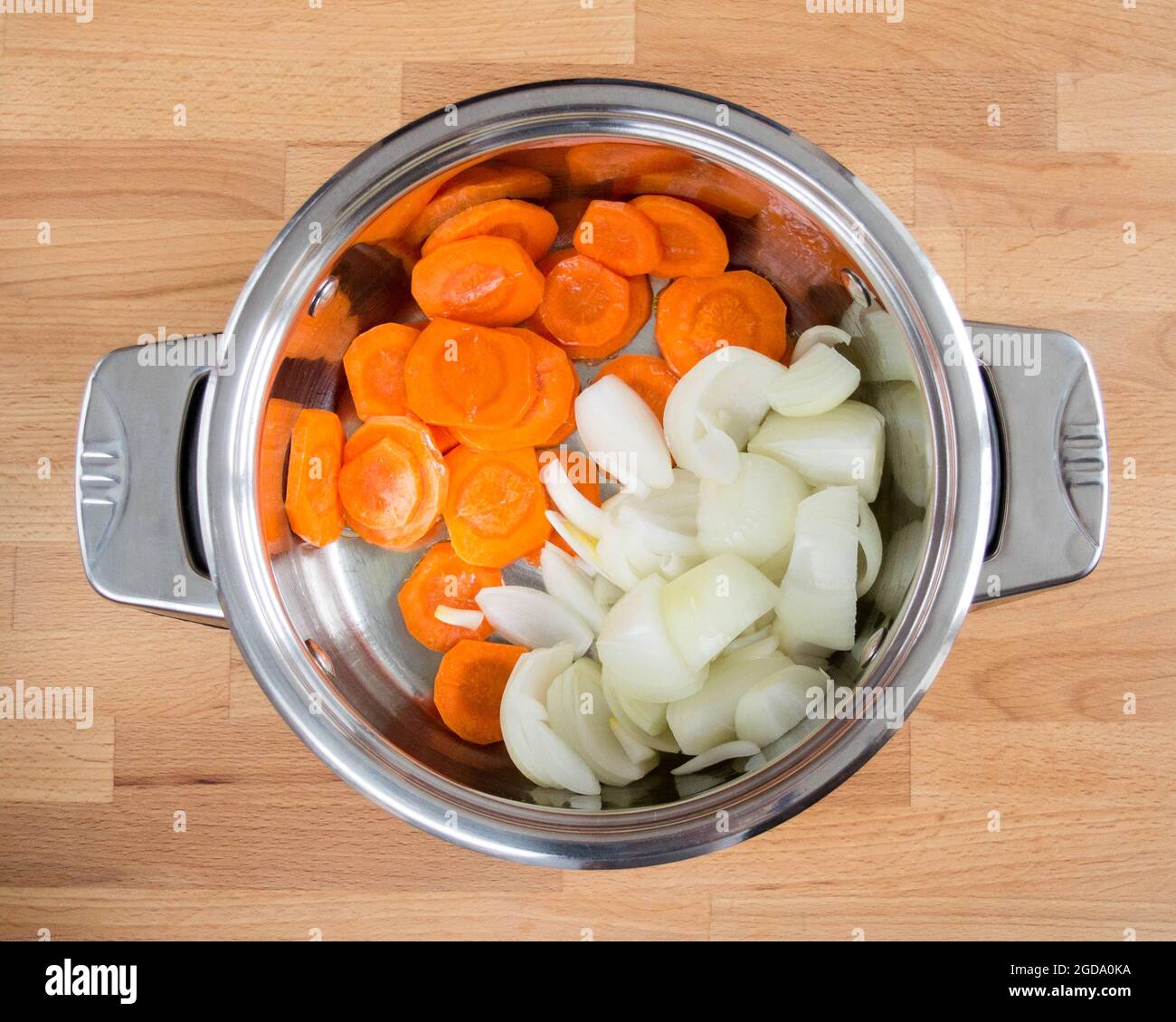.Chopped onions and carrots in a saucepan. Preparation for frying. Stock Photo