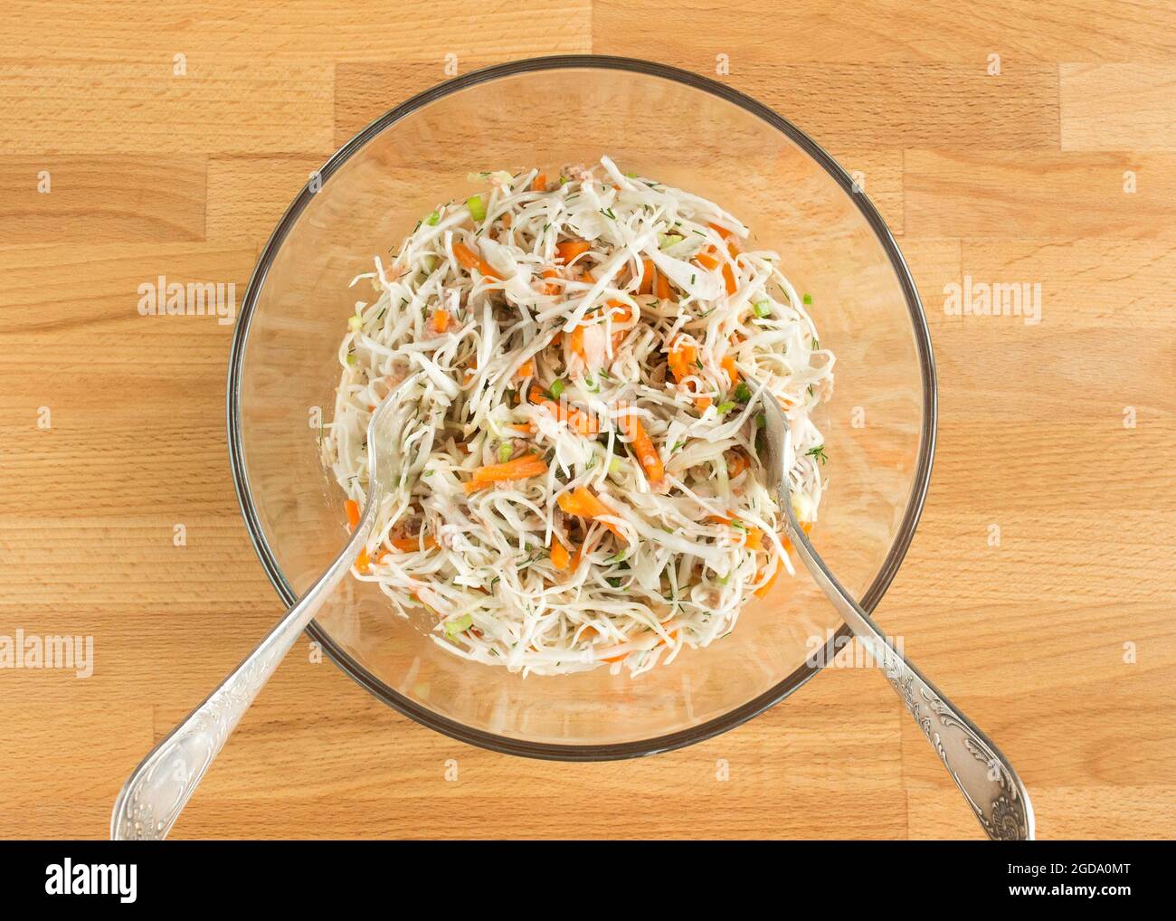 Vegetable salad with canned fish in a transparent bowl. Forks stick out. Stock Photo