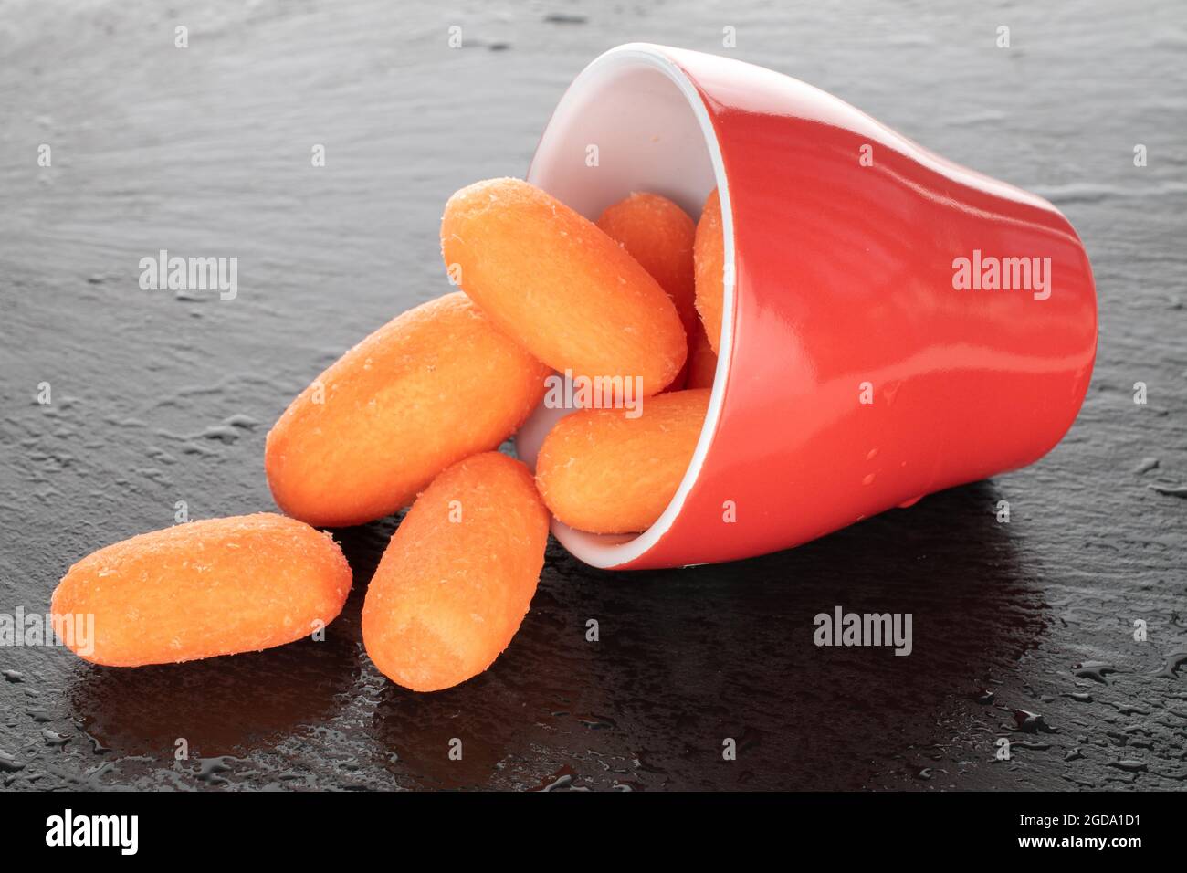 Bright orange juicy, peeled mini carrots on a slate serving board, close-up. Stock Photo