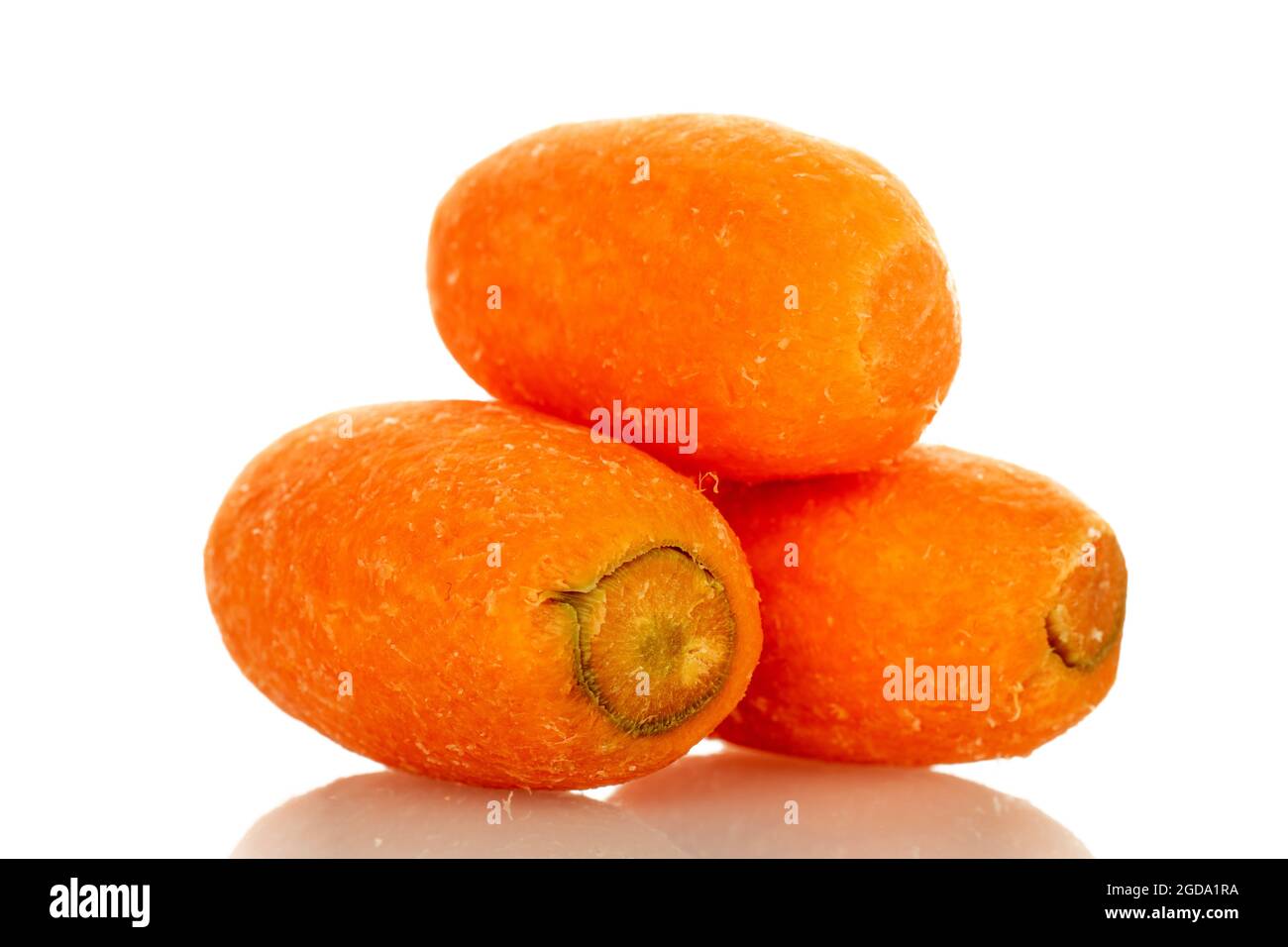 Three bright orange organic mini carrots, close-up, on a white background. Stock Photo