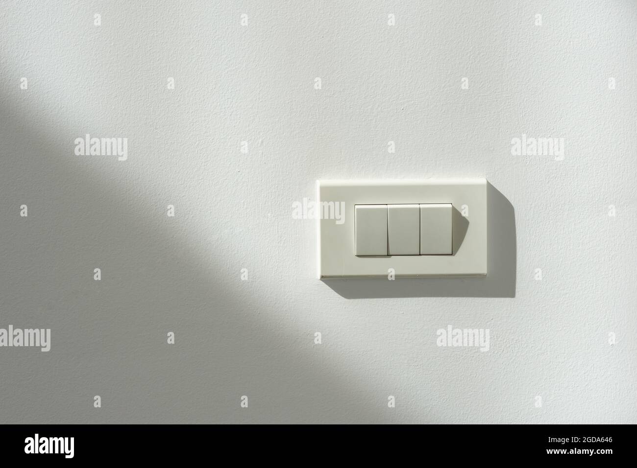 White switch power on a white wall with light and shadow contrast. Stock Photo
